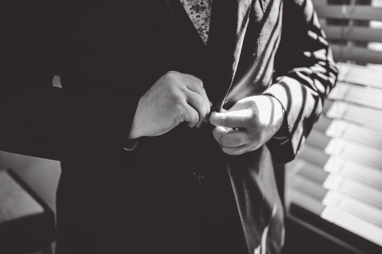 Black and white photo of formal wear adjustments in natural window light.