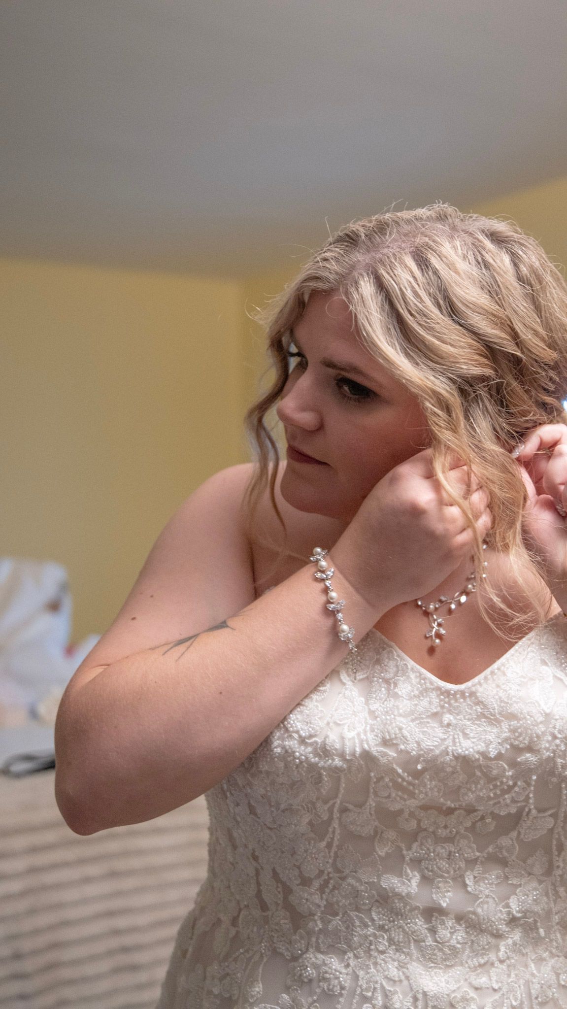 Close-up of bridal preparations showing detailed lace dress and jewelry.
