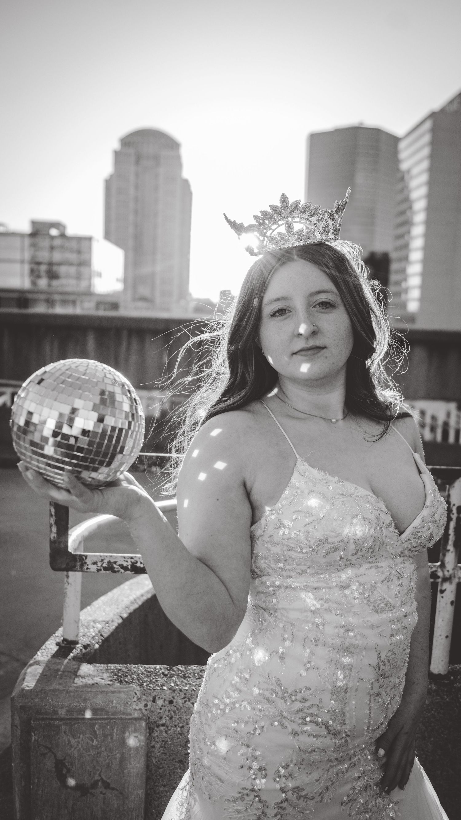 Black and white portraits with a sparkly dress and disco ball against city buildings.