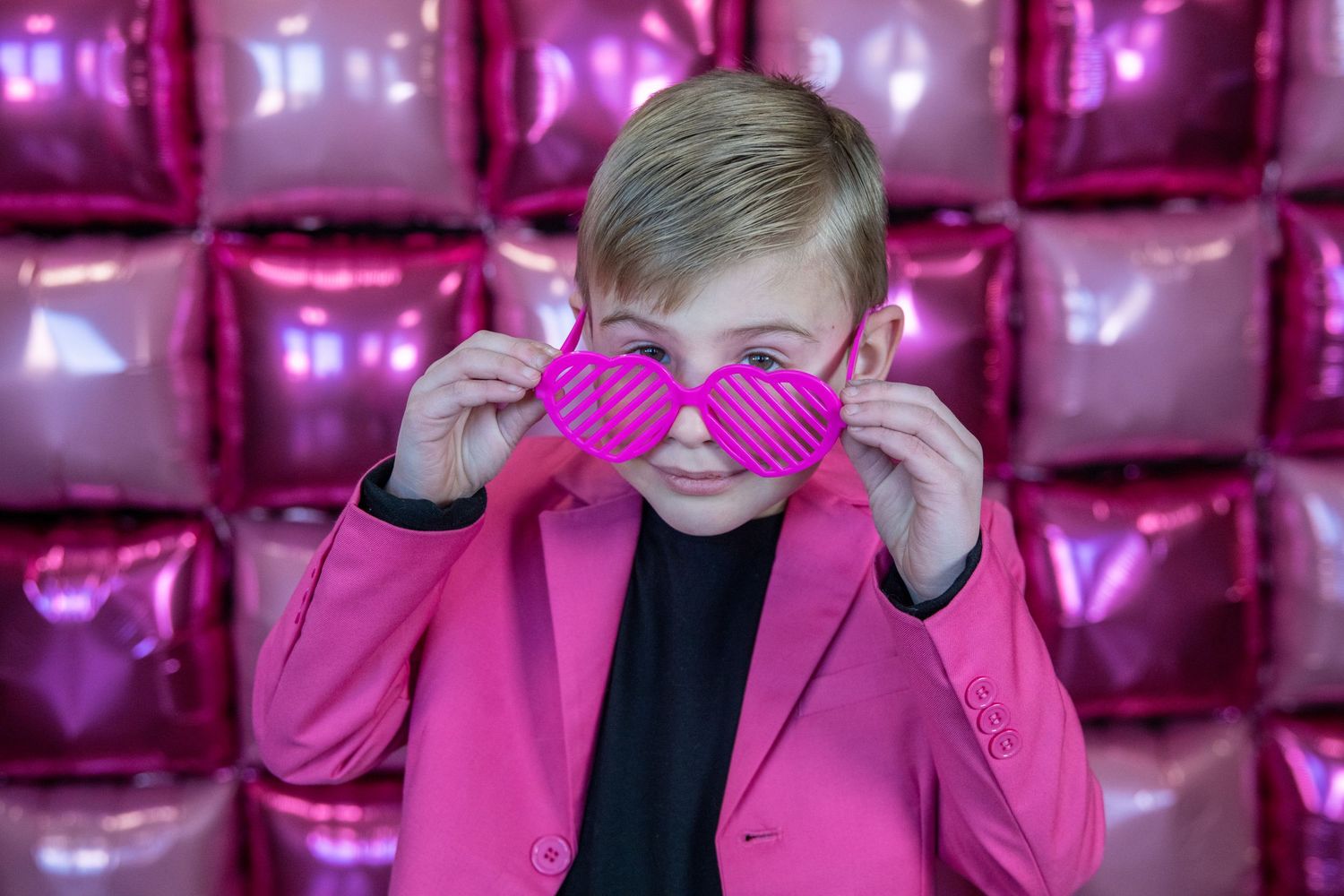 Pink metallic balloon wall backdrop with bright pink blazer fashion shoot.