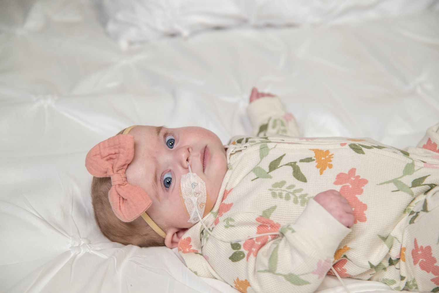 Infant wearing floral outfit with pink bow during studio photography session.