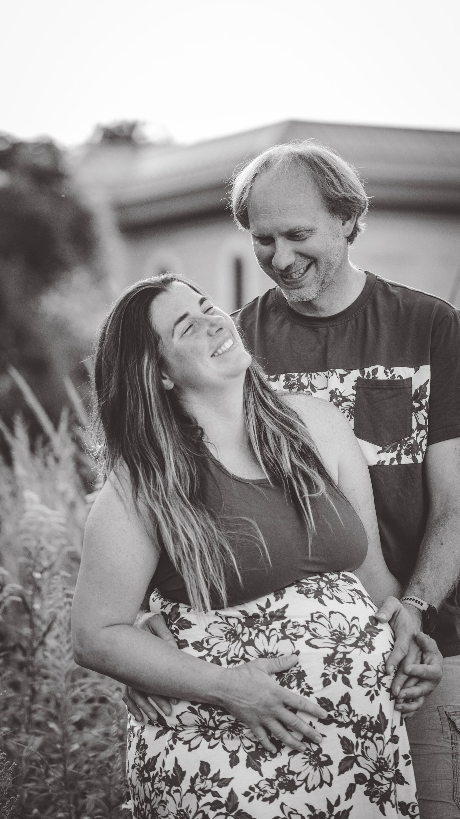 Black and white maternity photos showing tender moments between a couple in a natural outdoor setting.