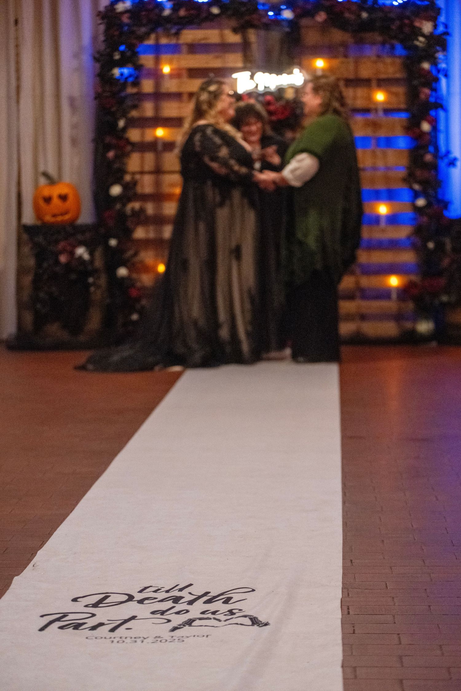 Wedding ceremony venue decorated with pumpkins, blue lighting and floral arrangements.