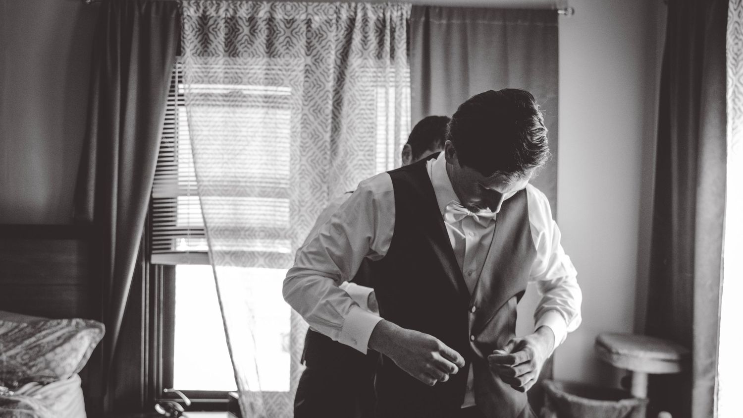 Groomsmen in black suits and red ties adjusting their formal attire before a wedding ceremony.