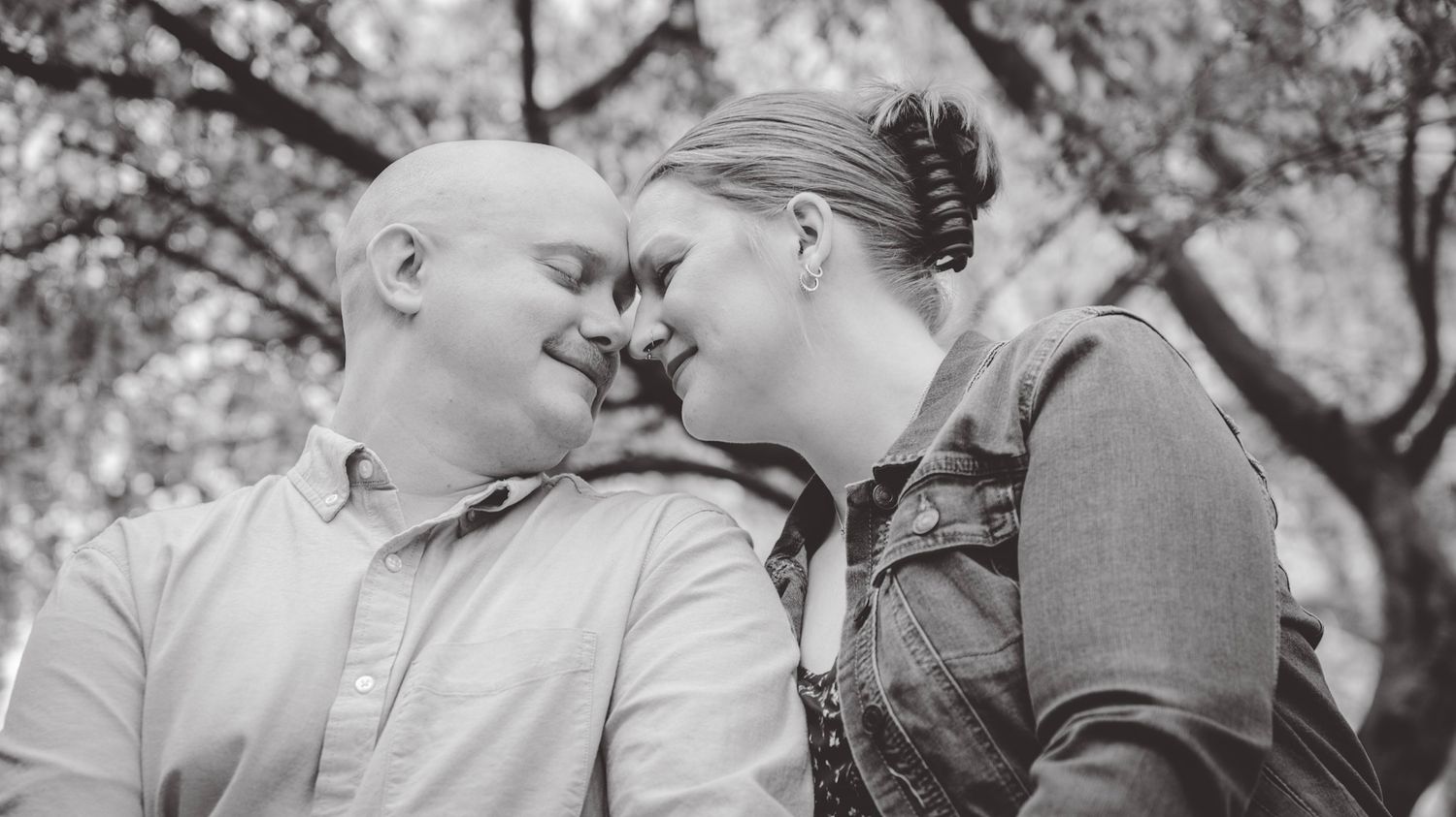 A tender black and white portrait of a couple sharing an intimate moment outdoors.