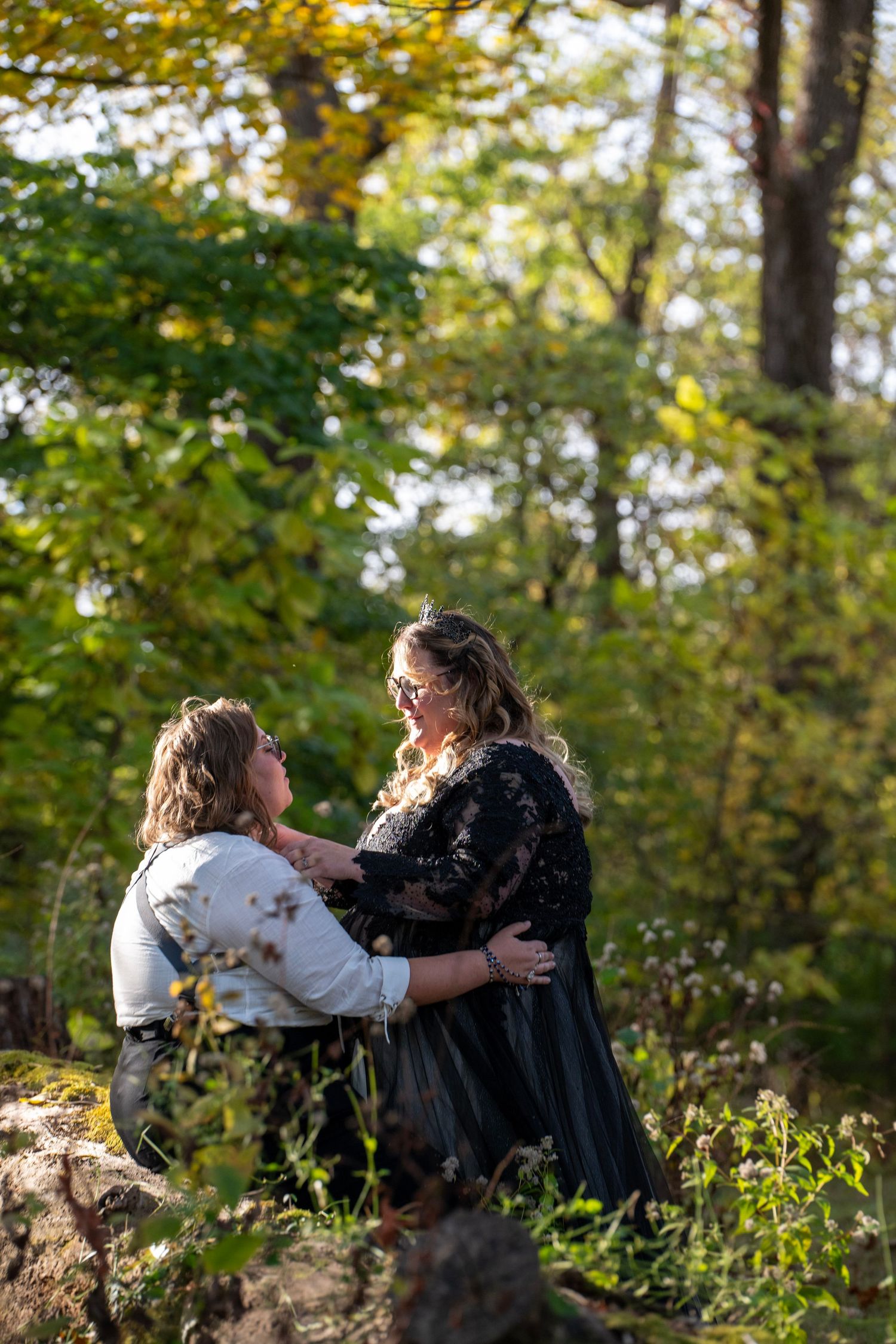 Couple sharing a tender moment against a backdrop of autumn trees and foliage.
