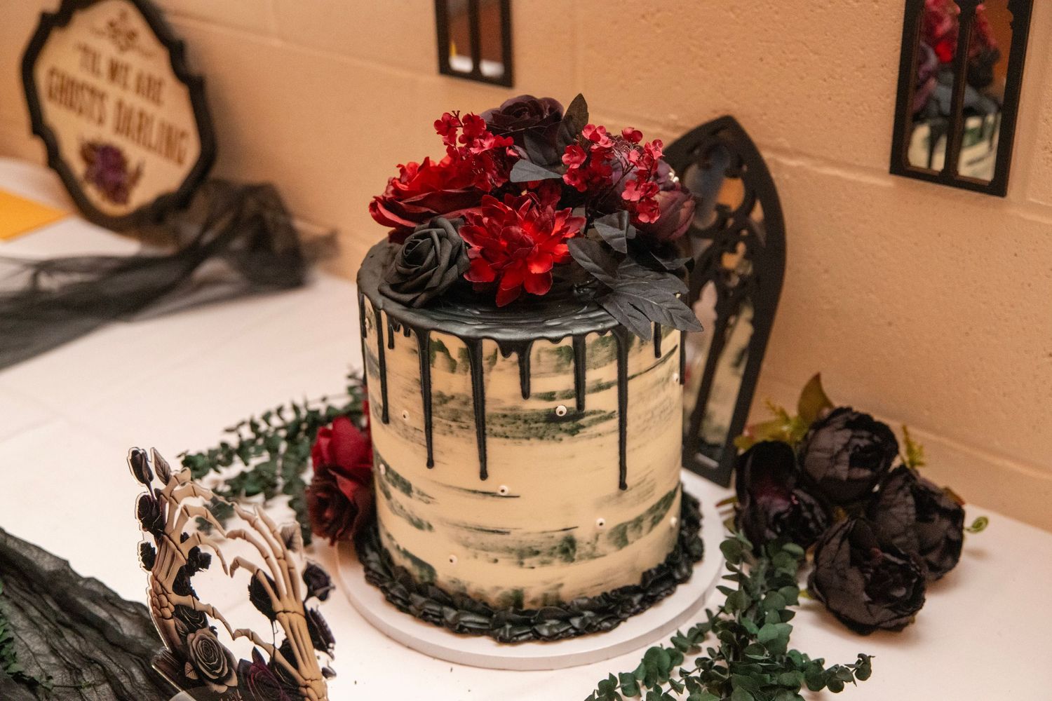 Elegant dessert table with dark themed wedding cake and gothic decorations.