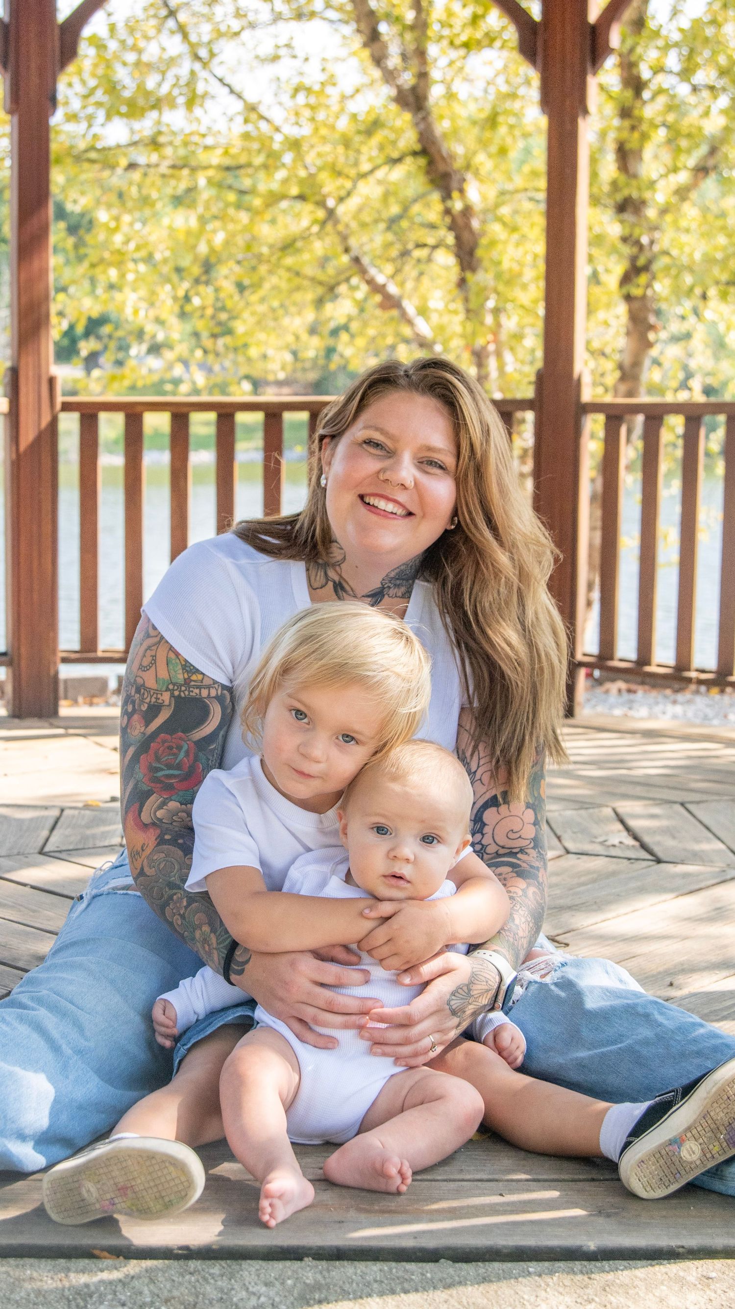 Family portrait session with matching outfits on a sunlit wooden deck.
