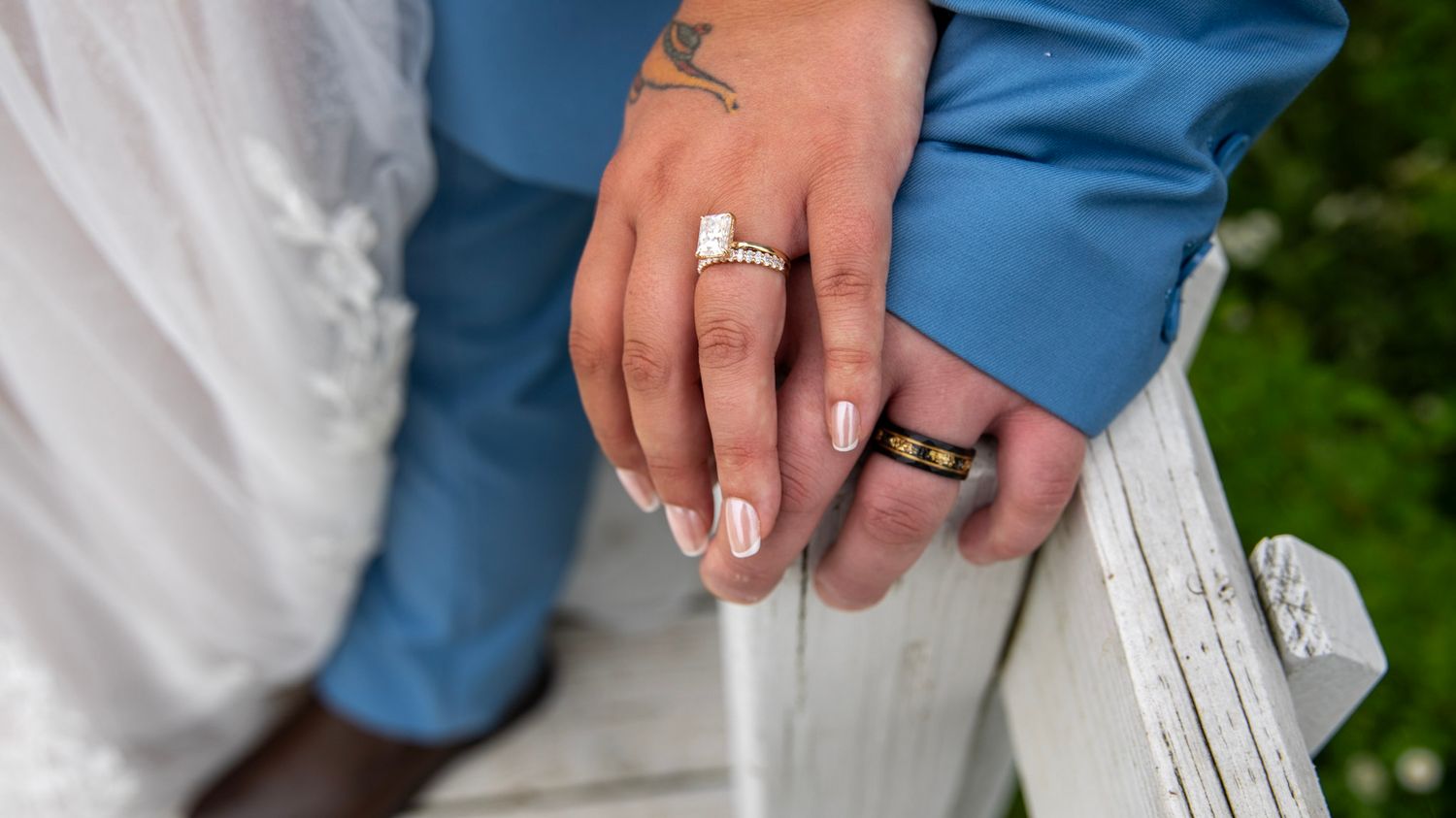 Close-up details of wedding rings and hands during an outdoor ceremony.
