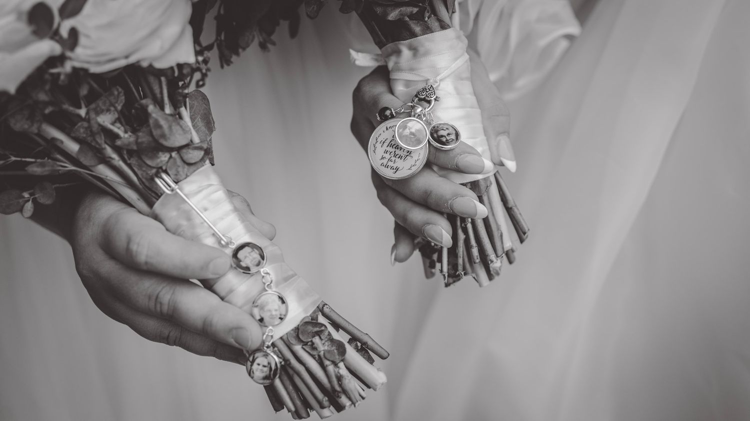 Black and white detail shot of hands holding delicate wedding bouquets.