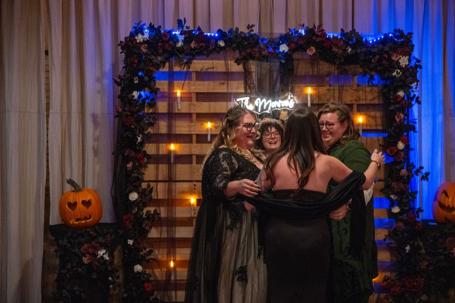 Rustic wedding venue with wooden pallet wall, blue lighting and seasonal decorations.
