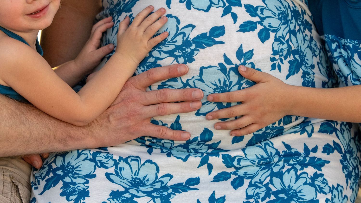 Artistic close-up of hands resting on a blue and white floral patterned dress.