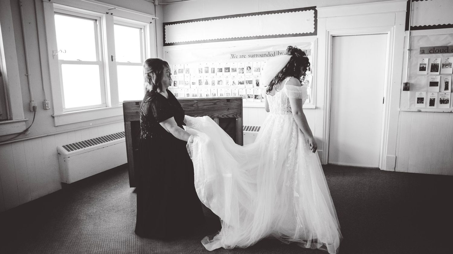 Panoramic black and white view of a bright room with windows and wedding preparations.