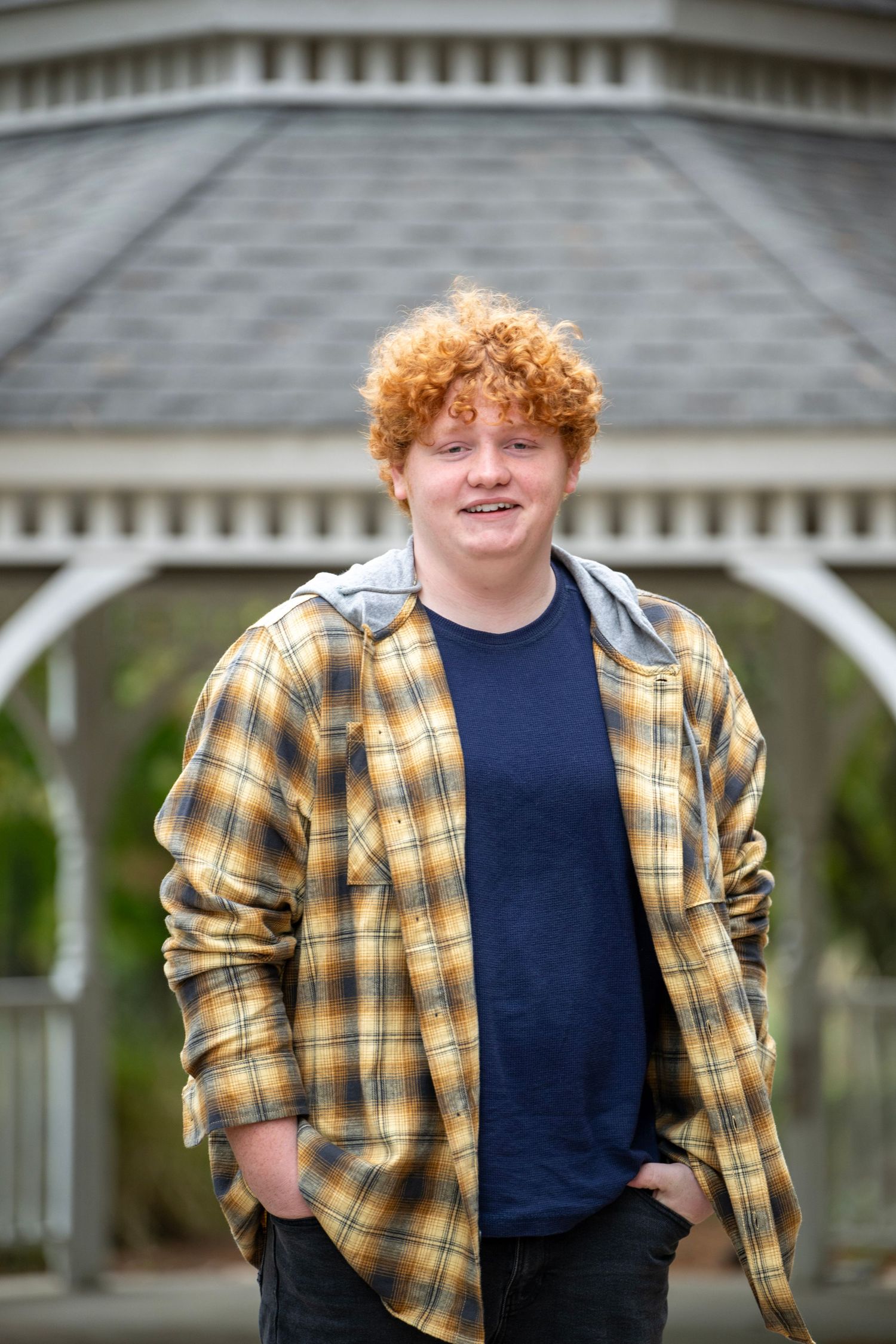 Casual portrait with plaid jacket against white gazebo background.