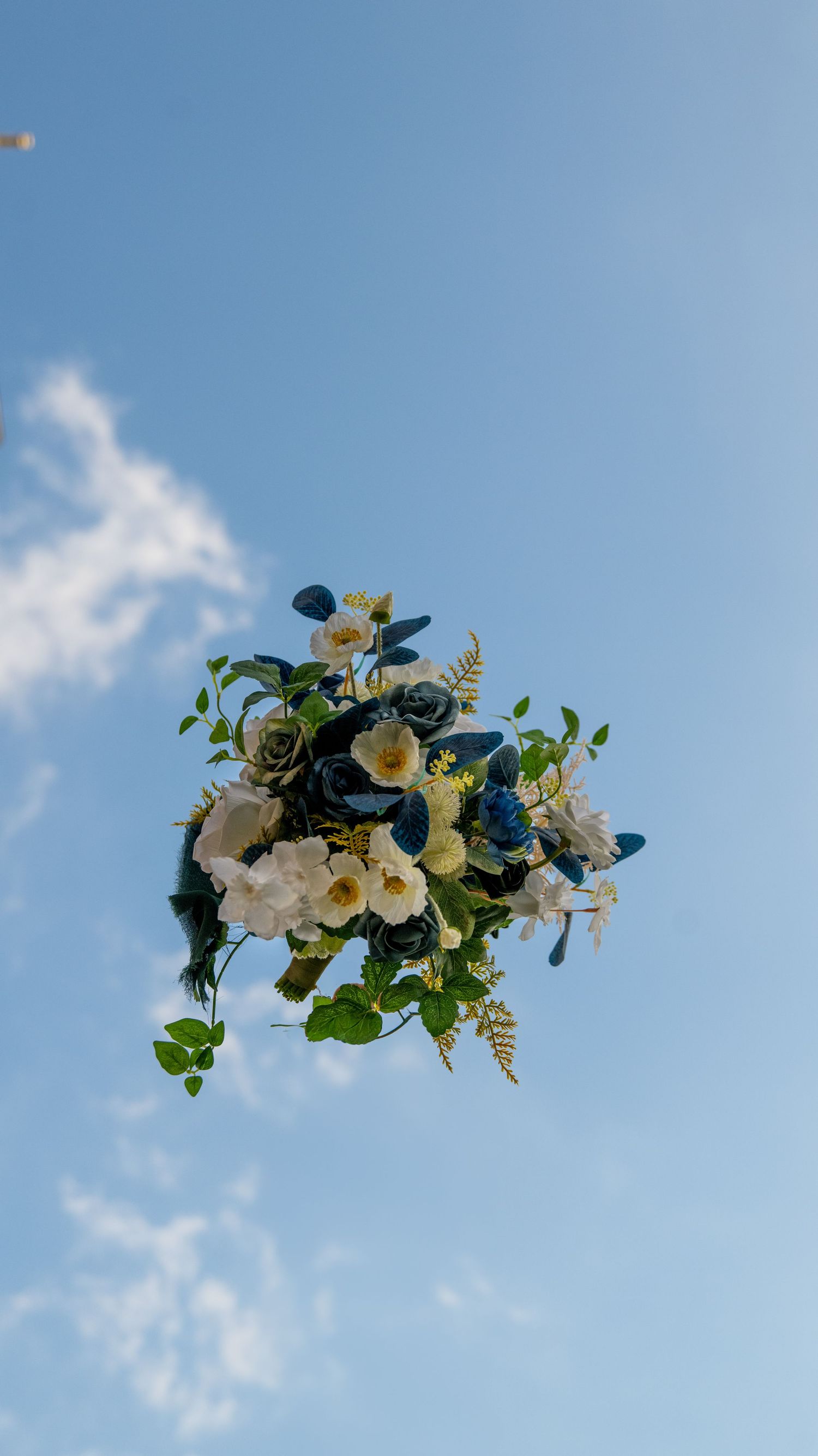 Floral wedding arch decorations with white flowers against bright blue sky.