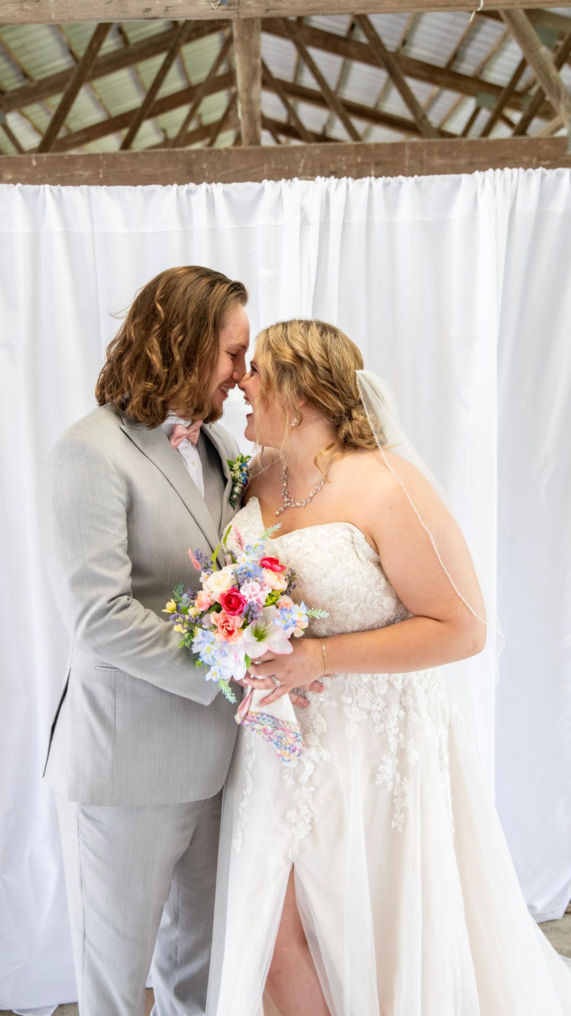 Wedding couple shares intimate moments in front of white backdrop.