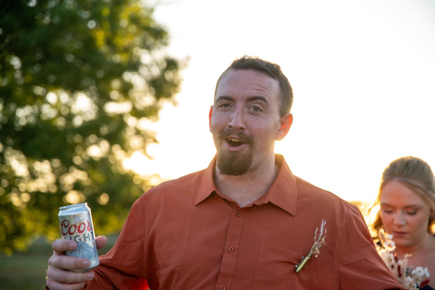 Wedding celebration outdoors with drinks and laughter during golden hour.