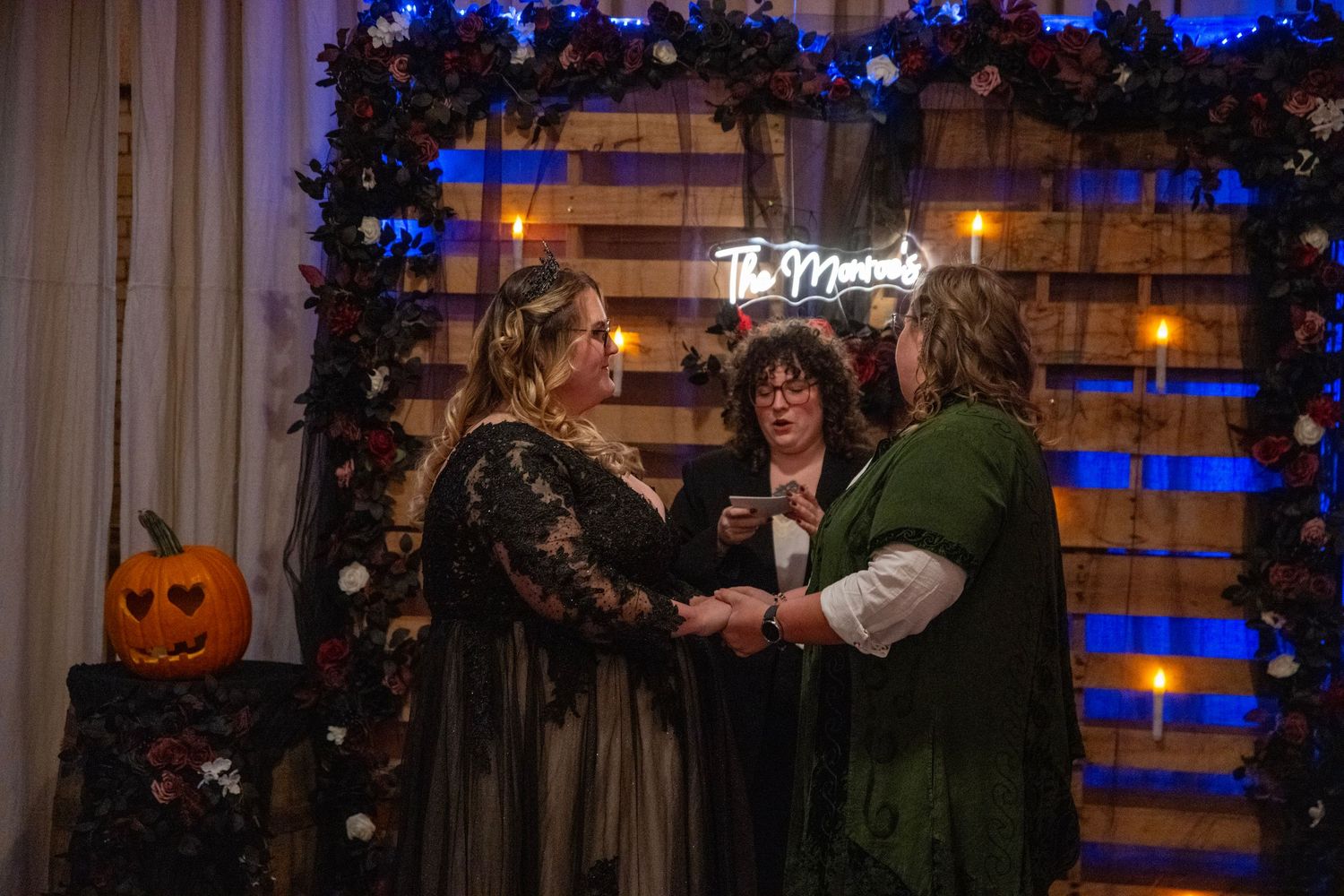 Wedding venue decorated with blue lights, floral garlands and Halloween pumpkin accents.