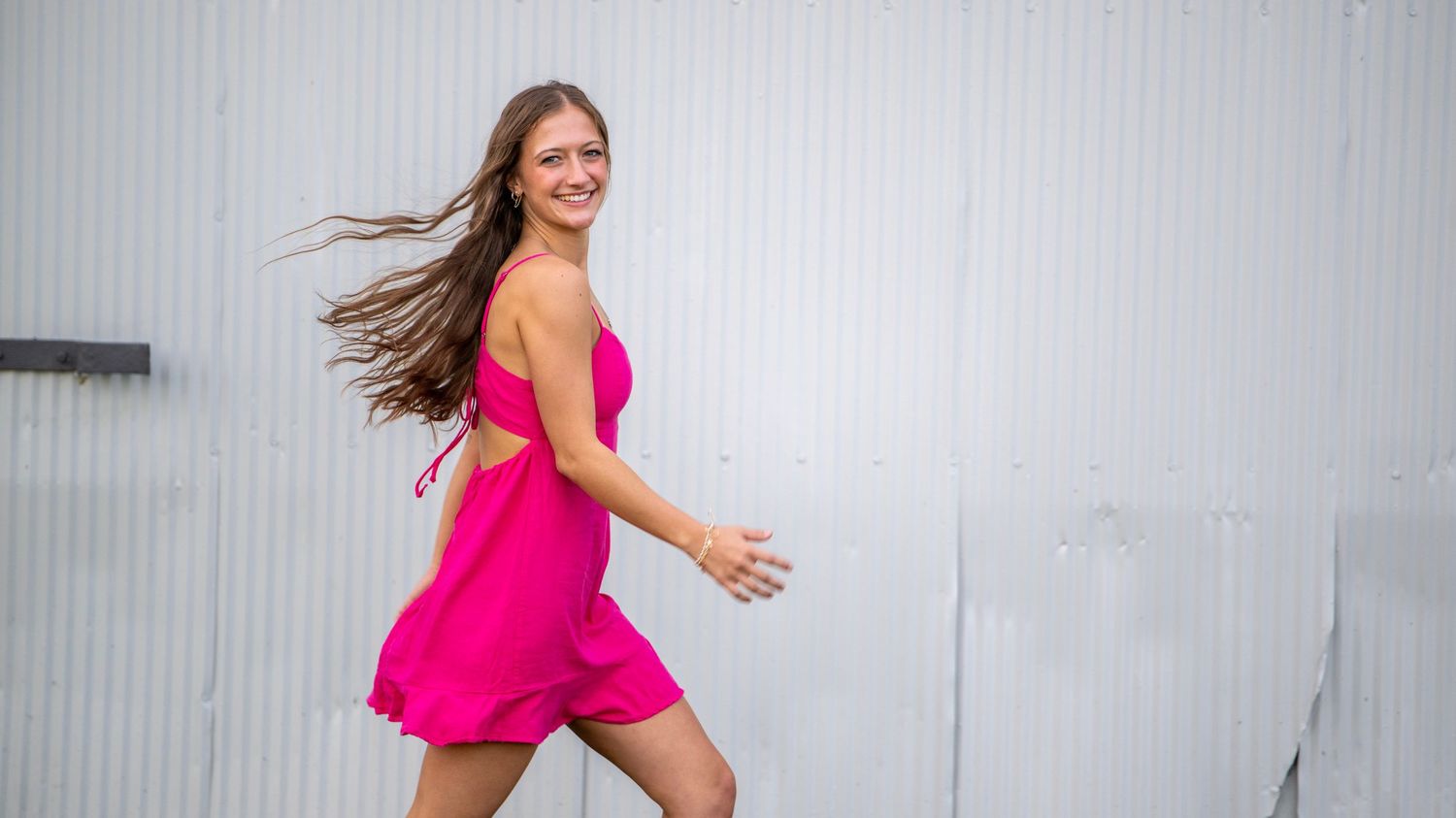 Dynamic movement shot against white wall wearing bright pink dress.