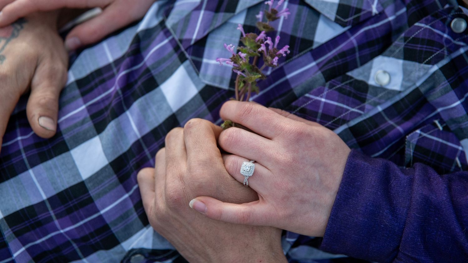 Close-up details of hands and plaid fabric showing tender moments between a couple.