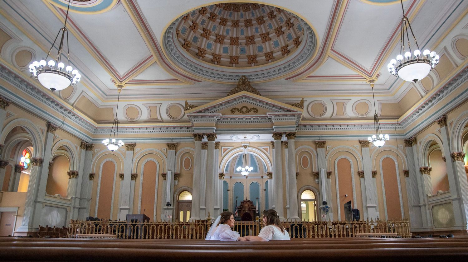 Panoramic view of an ornate historic ballroom with detailed ceiling architecture and chandeliers.