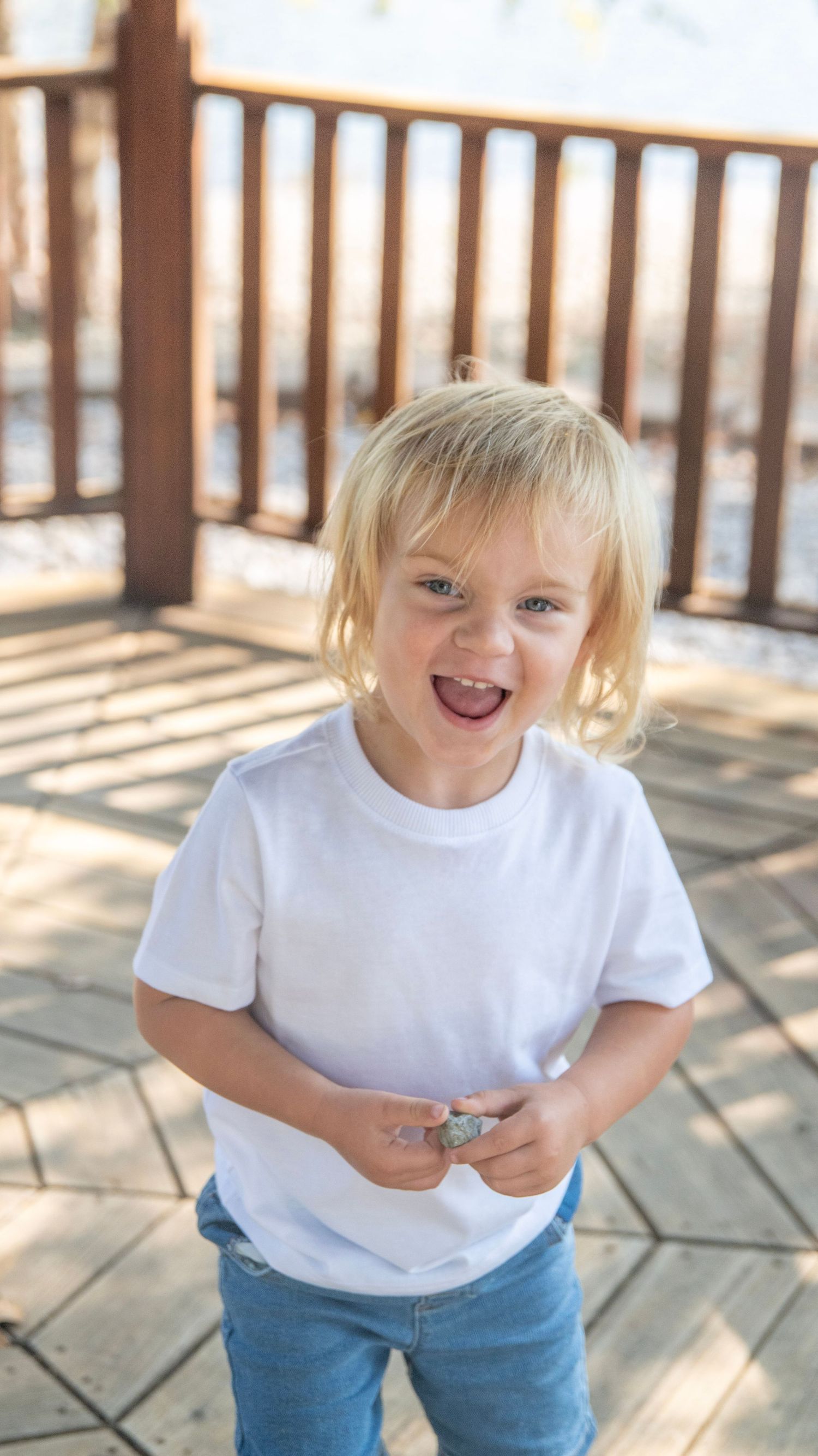 Candid childhood moments captured on a sunny deck with wooden railings.