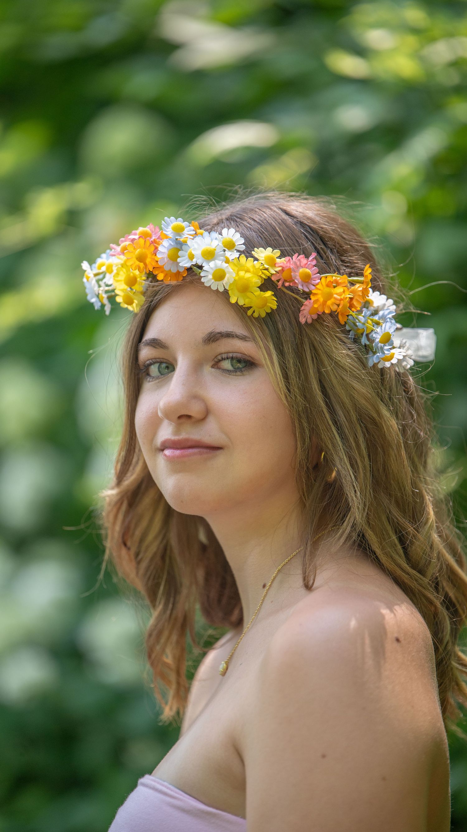Summer portrait with floral crown made of yellow daisies and white flowers in natural outdoor setting.