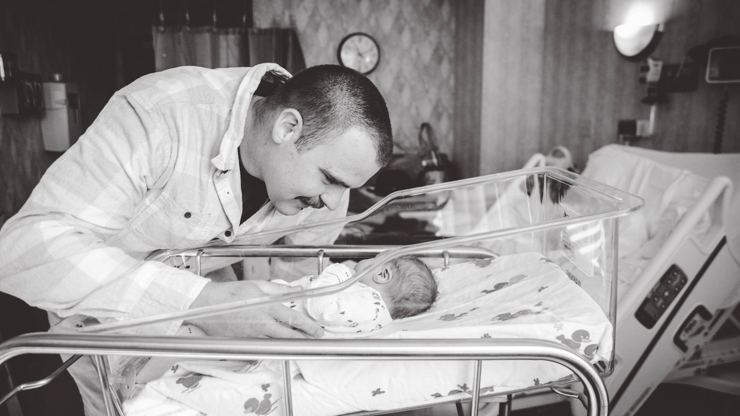 Black and white hospital scene showing medical equipment and bassinet.