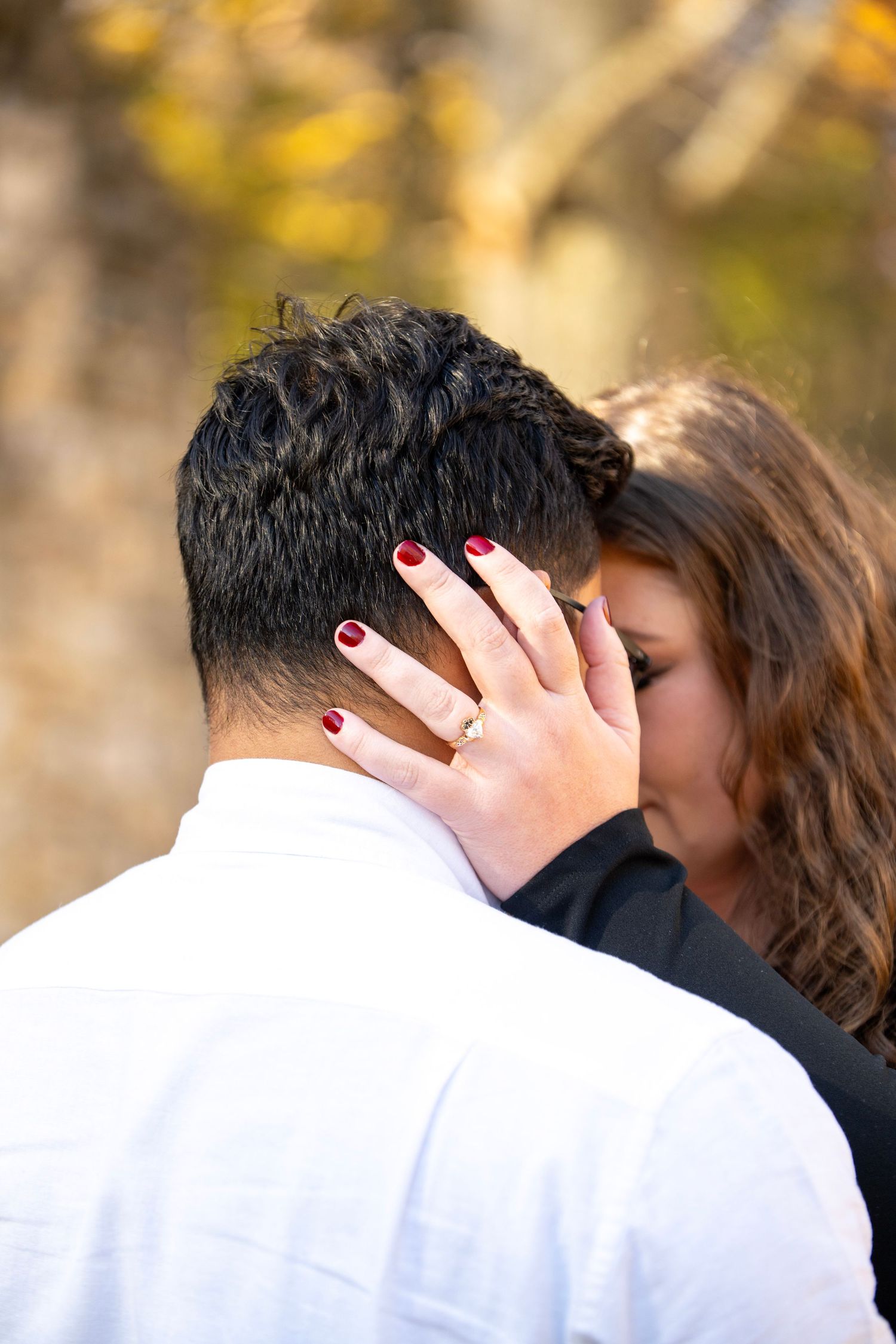 Close-up shot showing red nails and tender embrace during engagement photos.