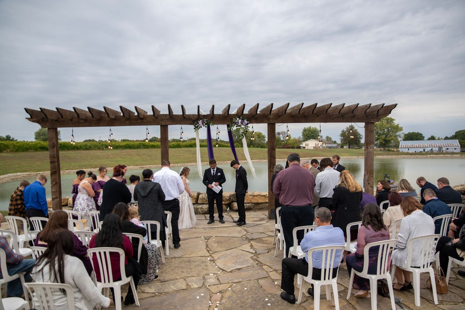 Wedding ceremony setup with wooden pergola and white chairs overlooking a scenic landscape.