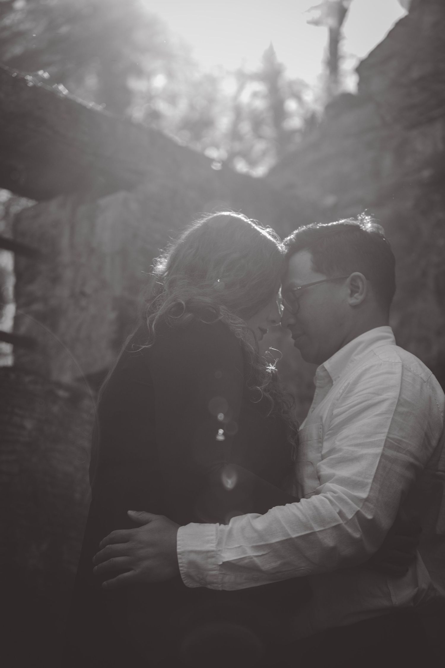 Black and white silhouette of an intimate moment between stone columns at sunset.