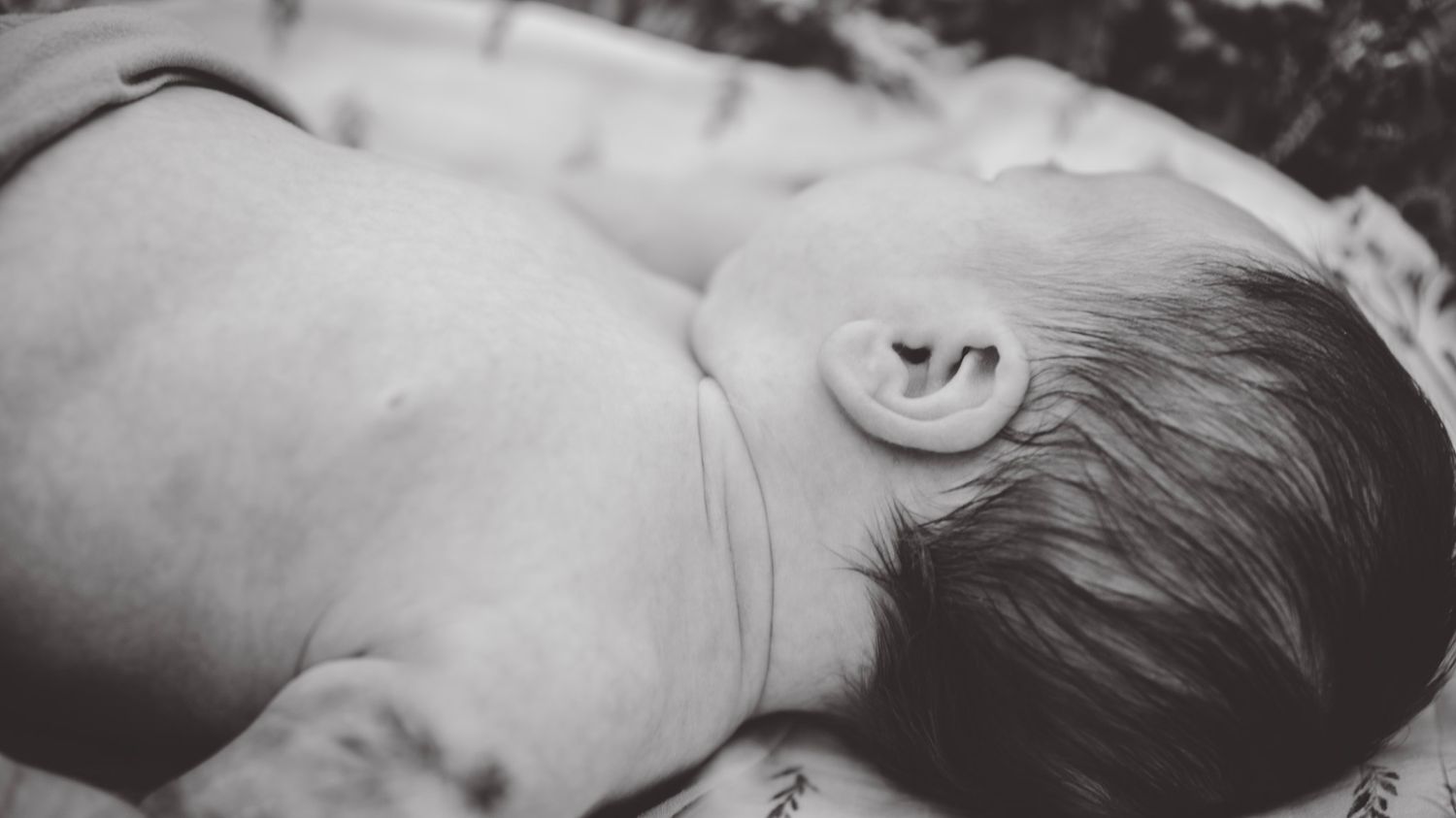 Black and white close-up of a sleeping newborn's profile.