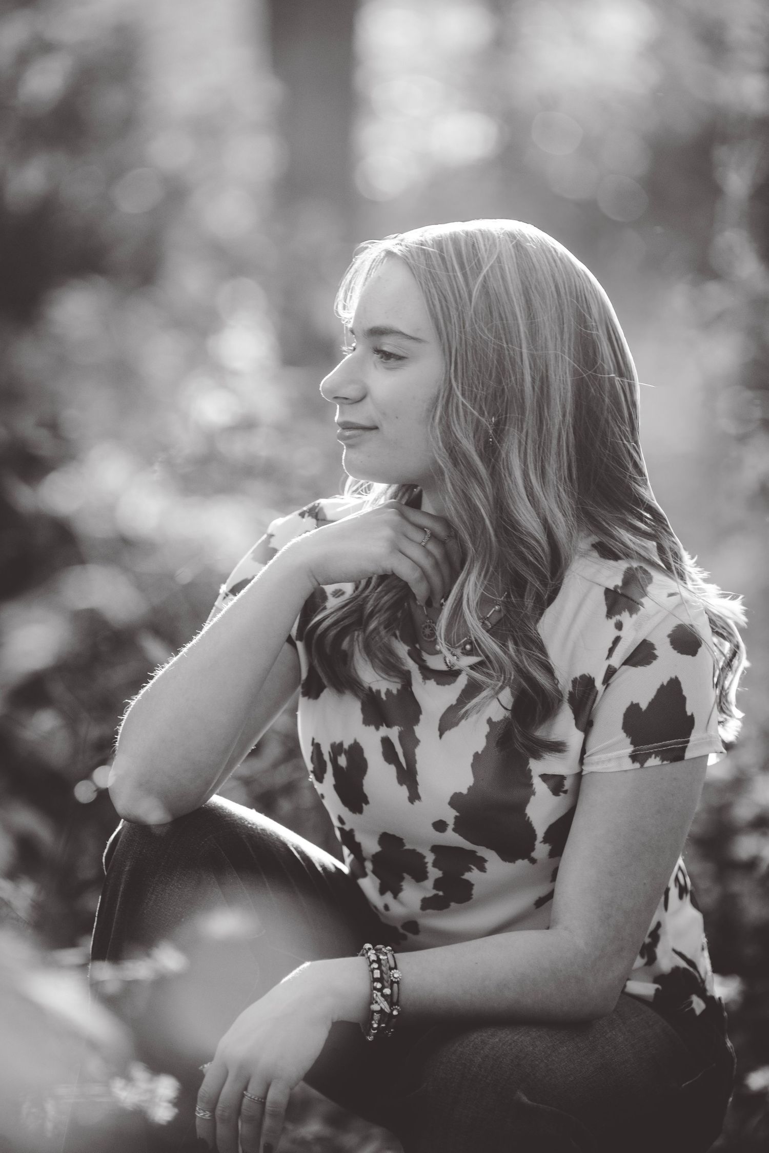 Black and white portrait series showing someone in a cow print top against a dreamy outdoor backdrop.
