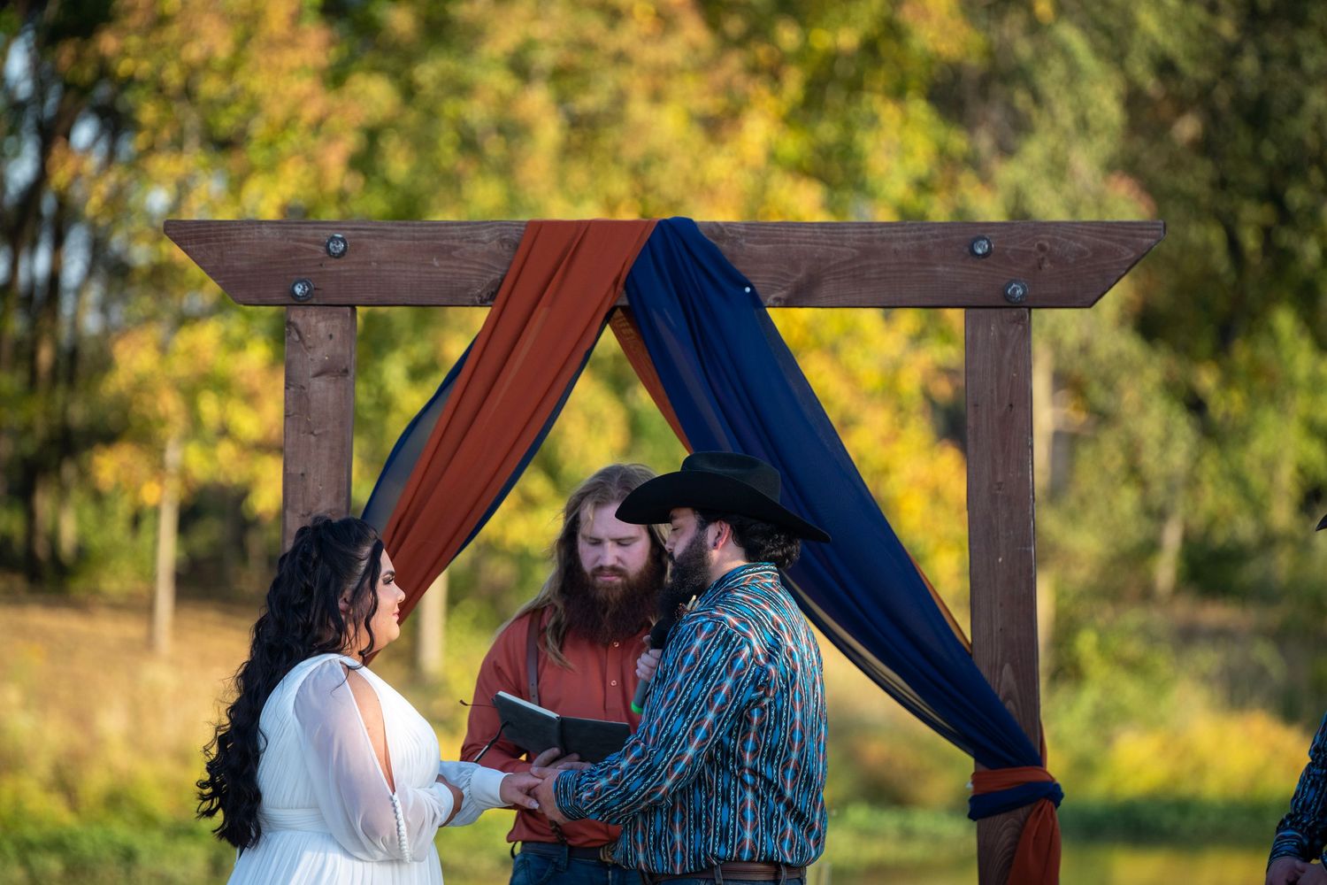 Rustic wooden pergola decorated for an outdoor autumn wedding ceremony.