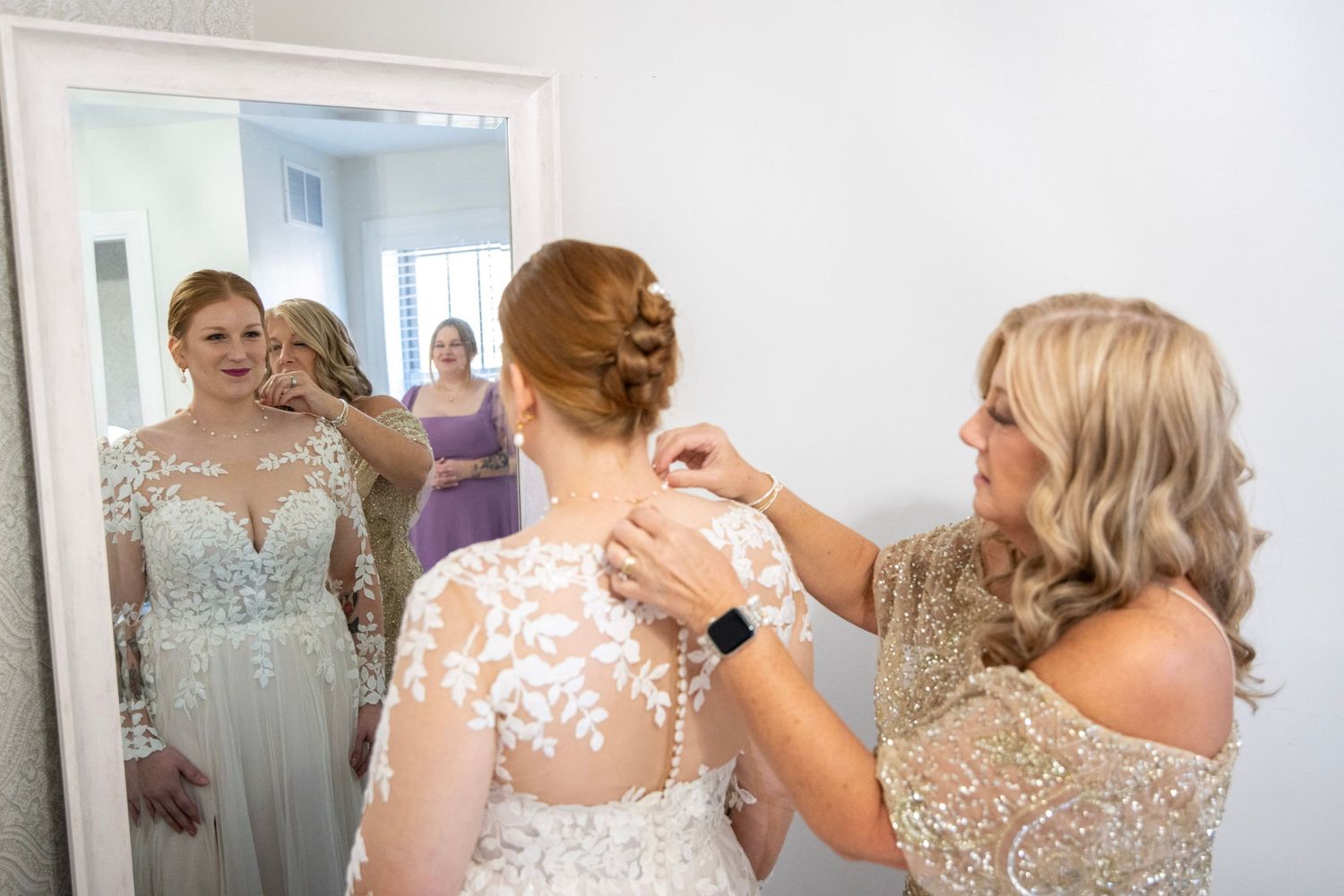 Bridesmaids in sequined gowns assist with final wedding day preparations.