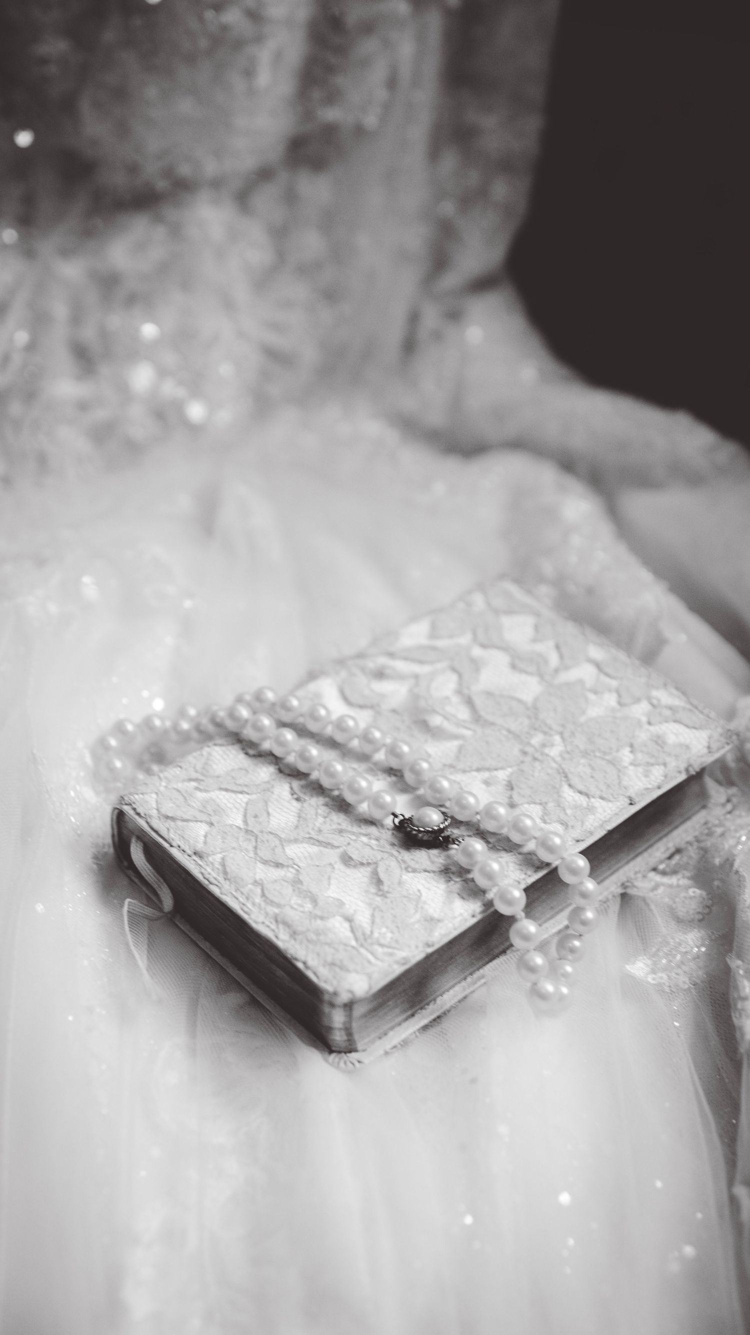 Close-up of an ornate white lace wedding book or album against tulle fabric.
