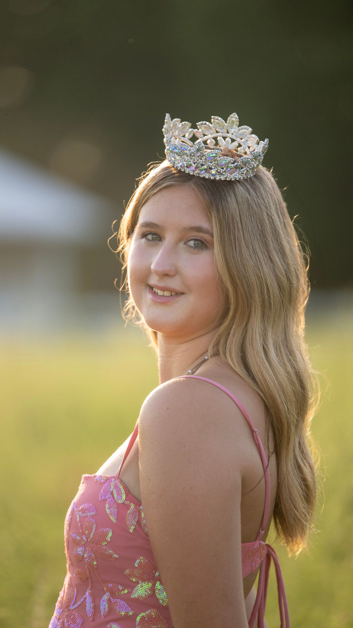 Golden hour portrait with backlit hair and sparkly accessories in a natural setting.