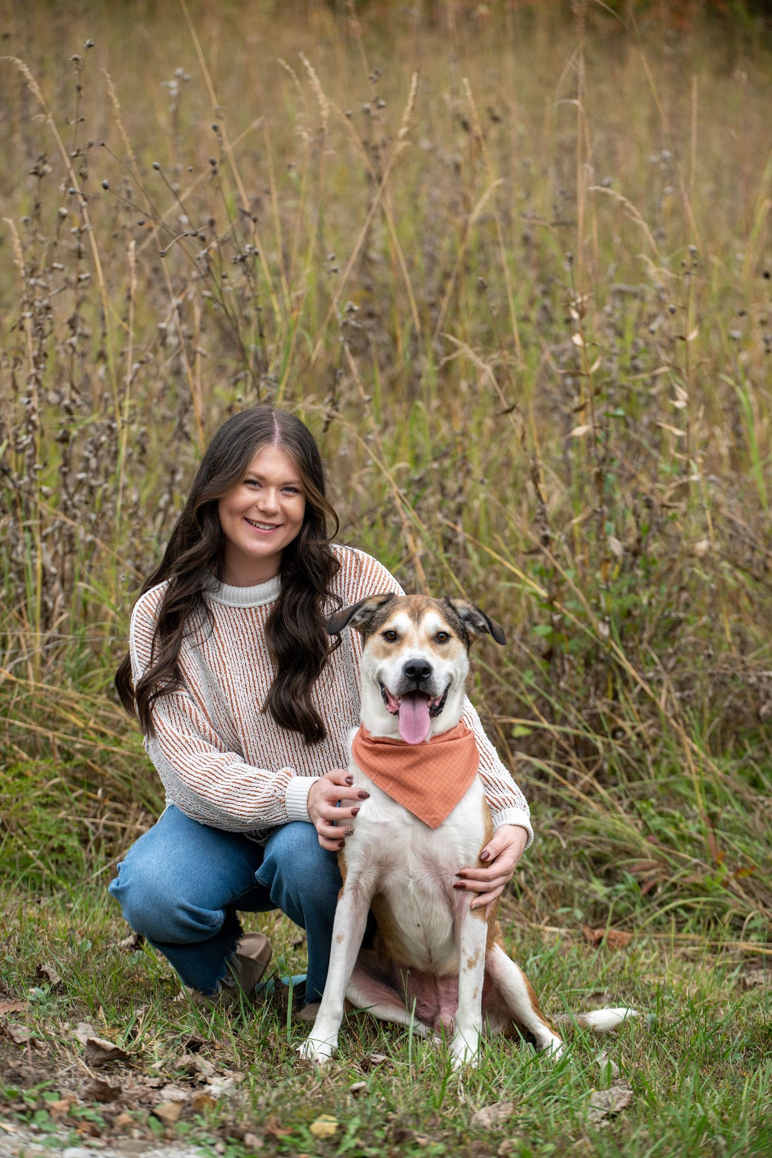 A happy dog and their companion share a joyful moment together outdoors among autumn grass.