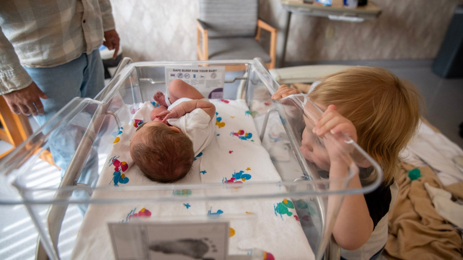 A touching moment in a hospital room with colorful decorations and medical equipment.