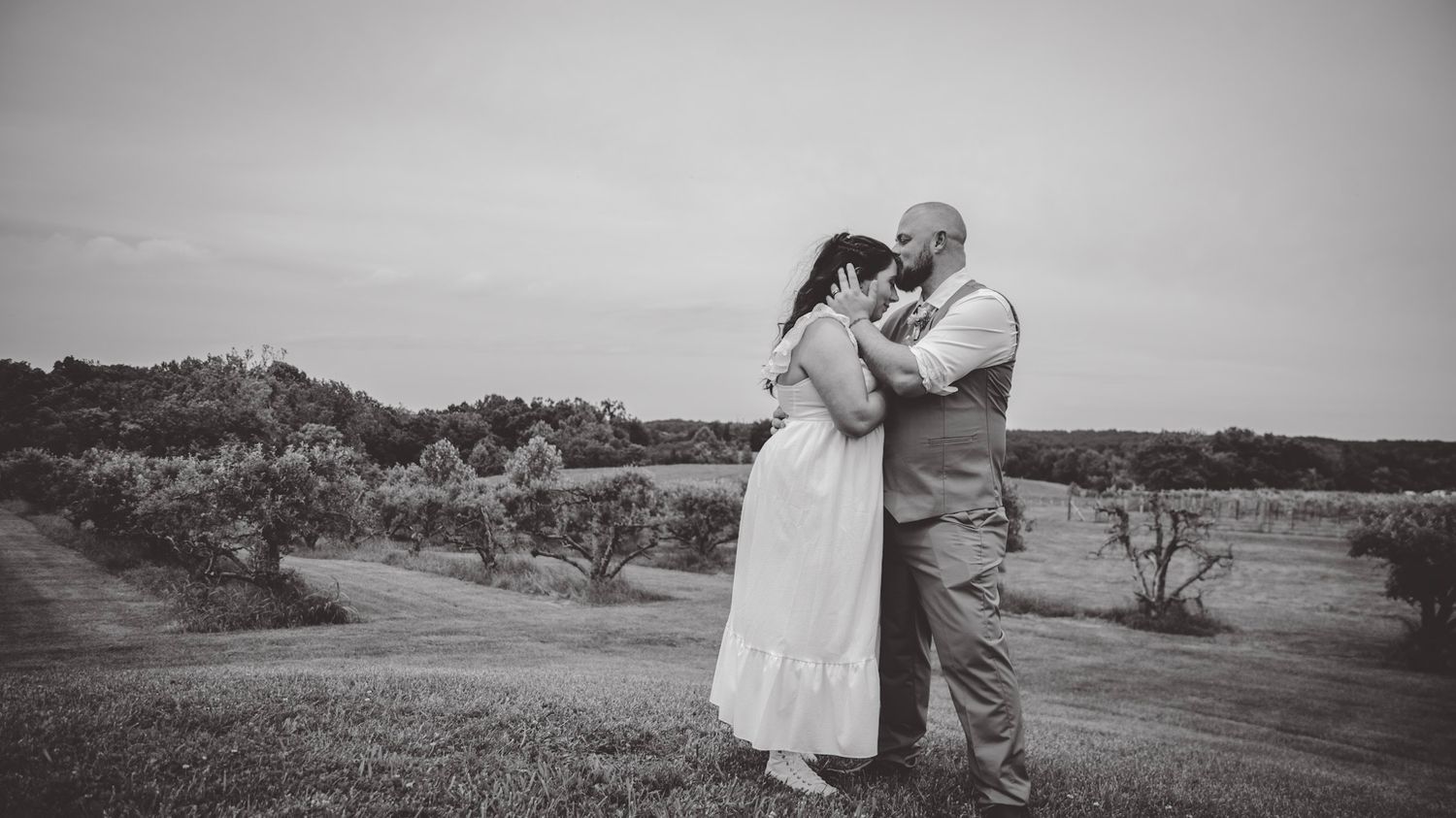 Black and white wedding photo series capturing intimate moments in a natural outdoor setting.
