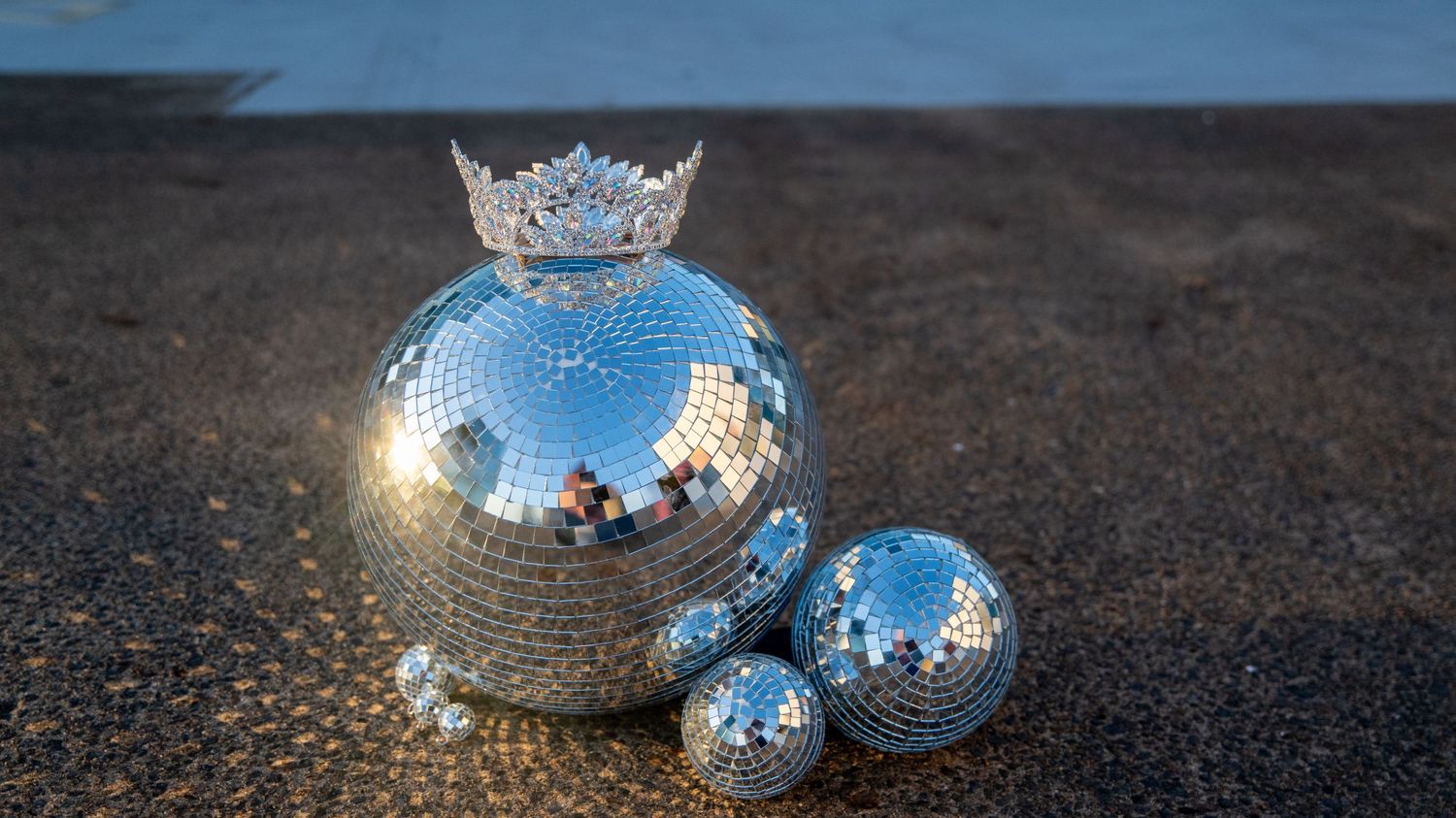Close-up shots of reflective disco balls on a dark textured surface.
