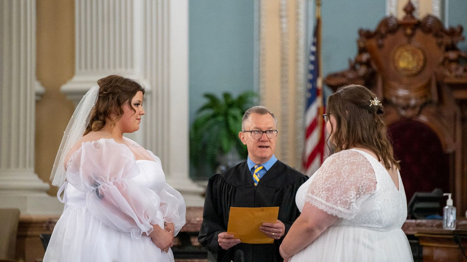 Wedding ceremony in progress inside a classical church with elegant columns and decor.