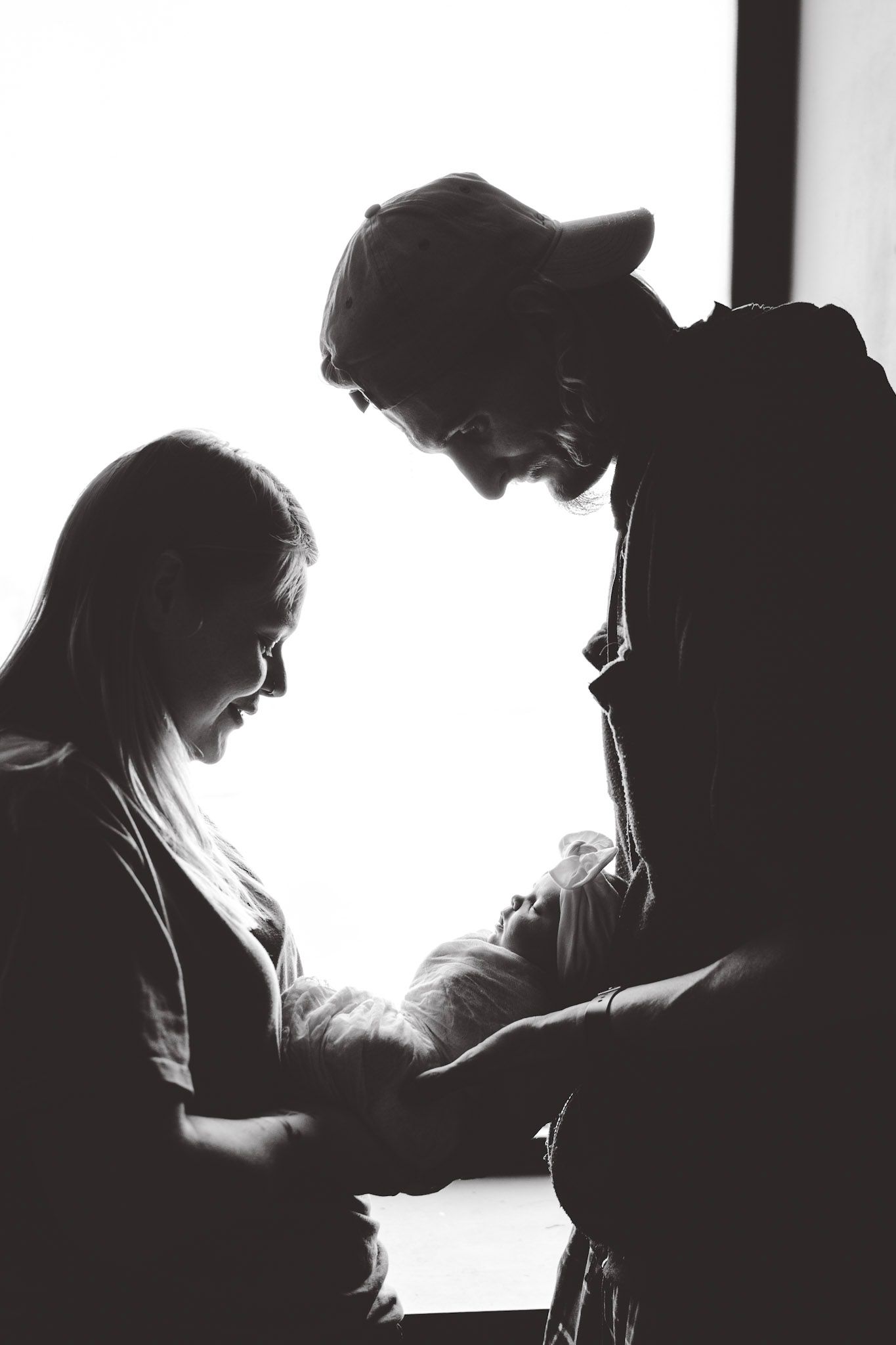 Dramatic black and white silhouettes of people in profile against bright background.