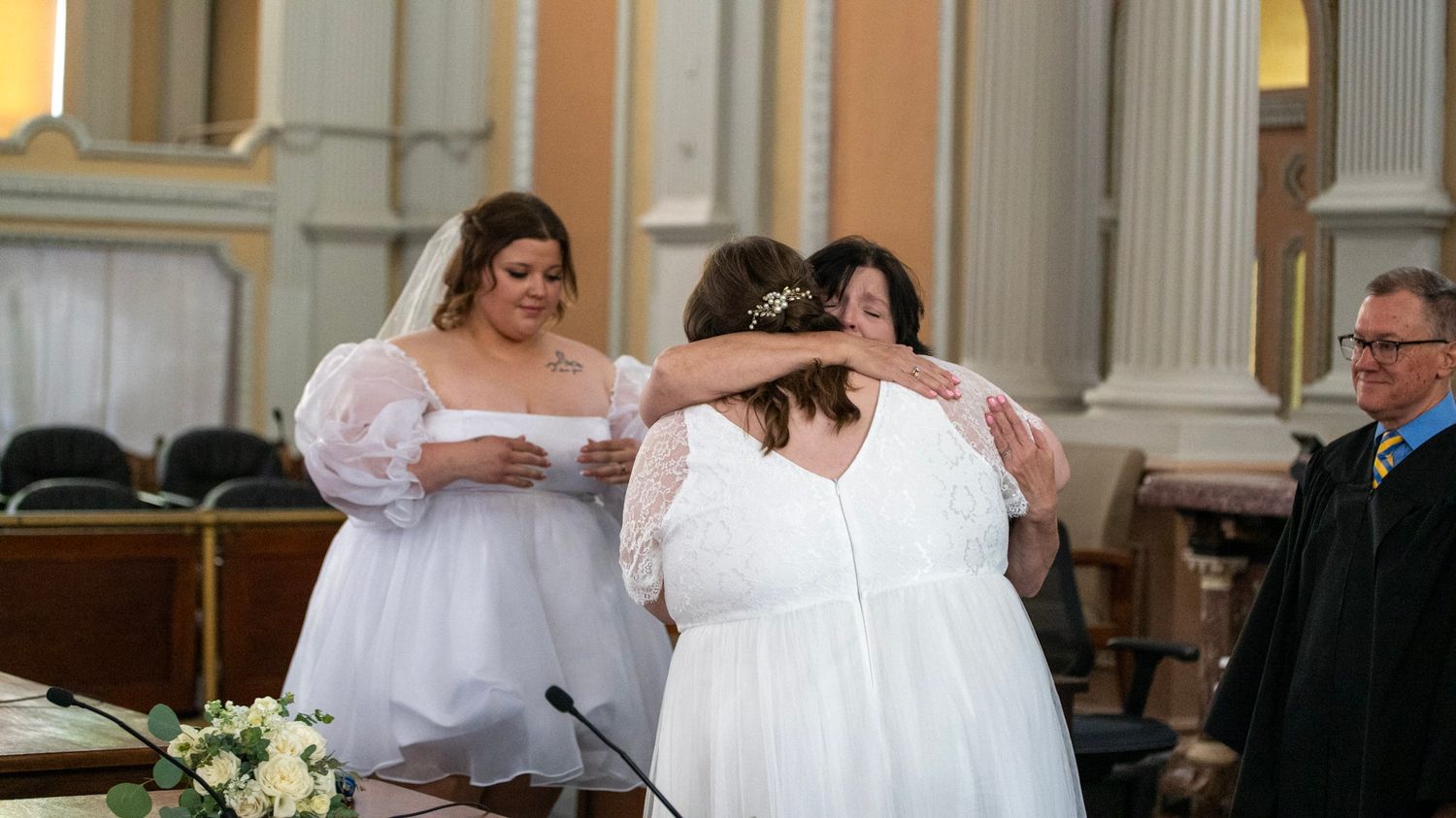 Wedding ceremony in historic courthouse with ornate columns and blue walls.