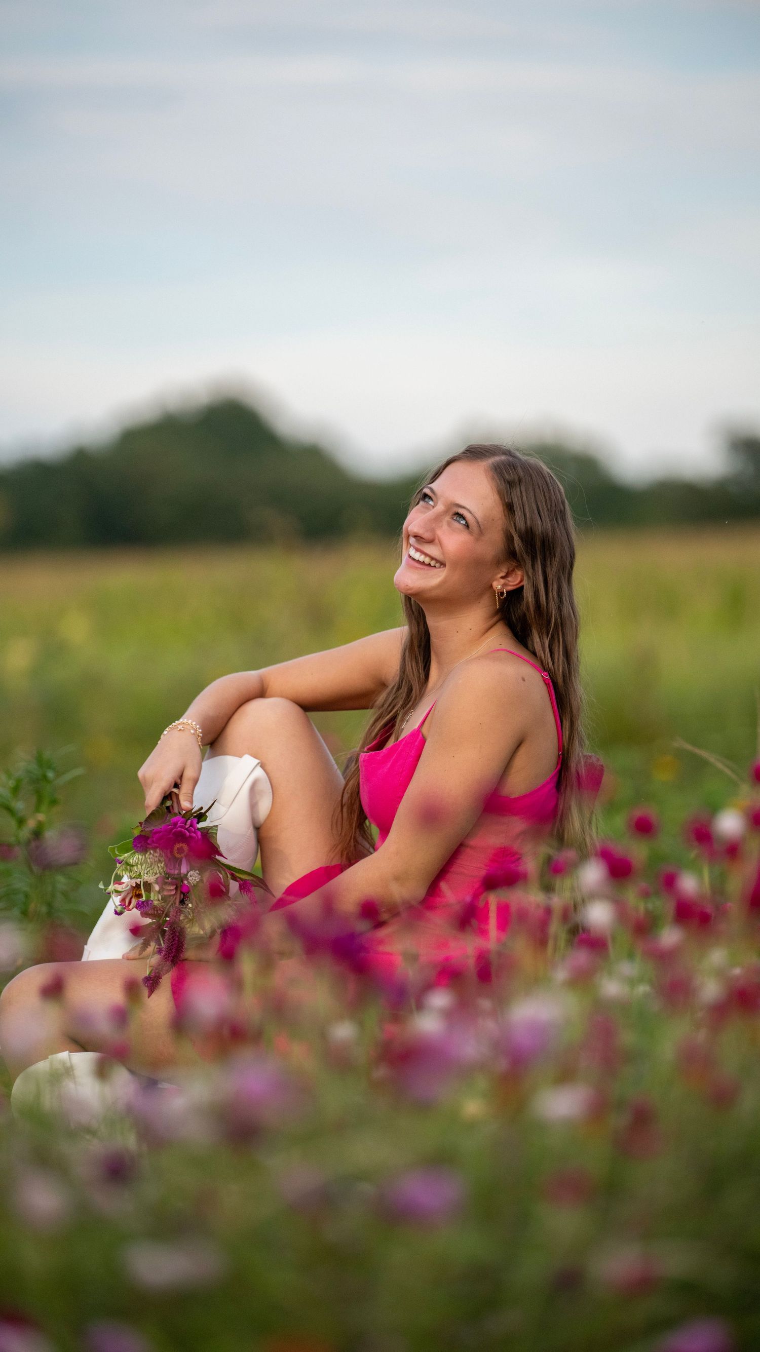 Artistic portrait in a field of vibrant pink wildflowers at sunset.