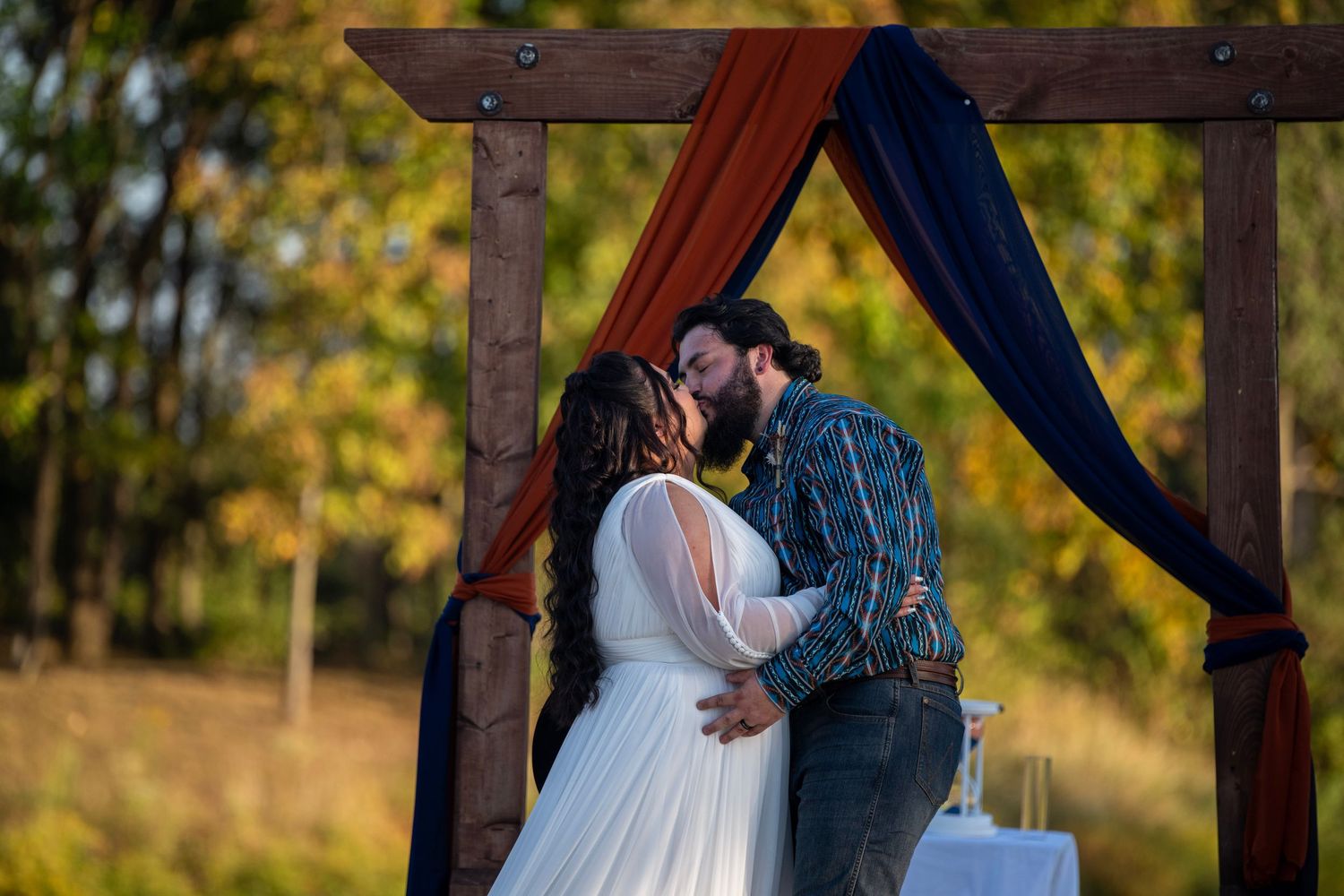 Intimate moment captured during outdoor wedding ceremony under wooden pergola.