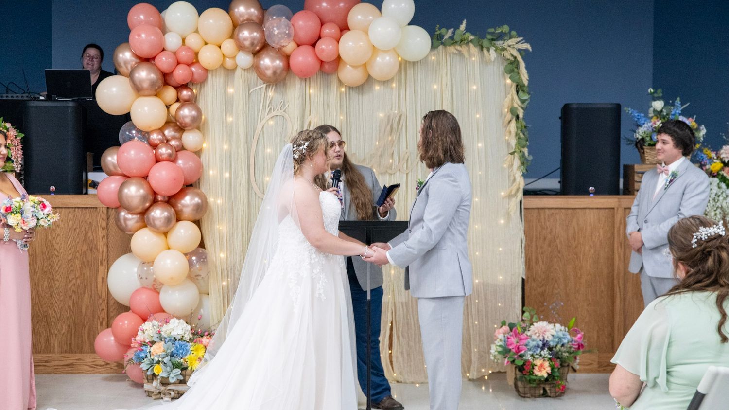 Wedding couple shares a romantic moment under an elegant balloon arch with pink and neutral tones.