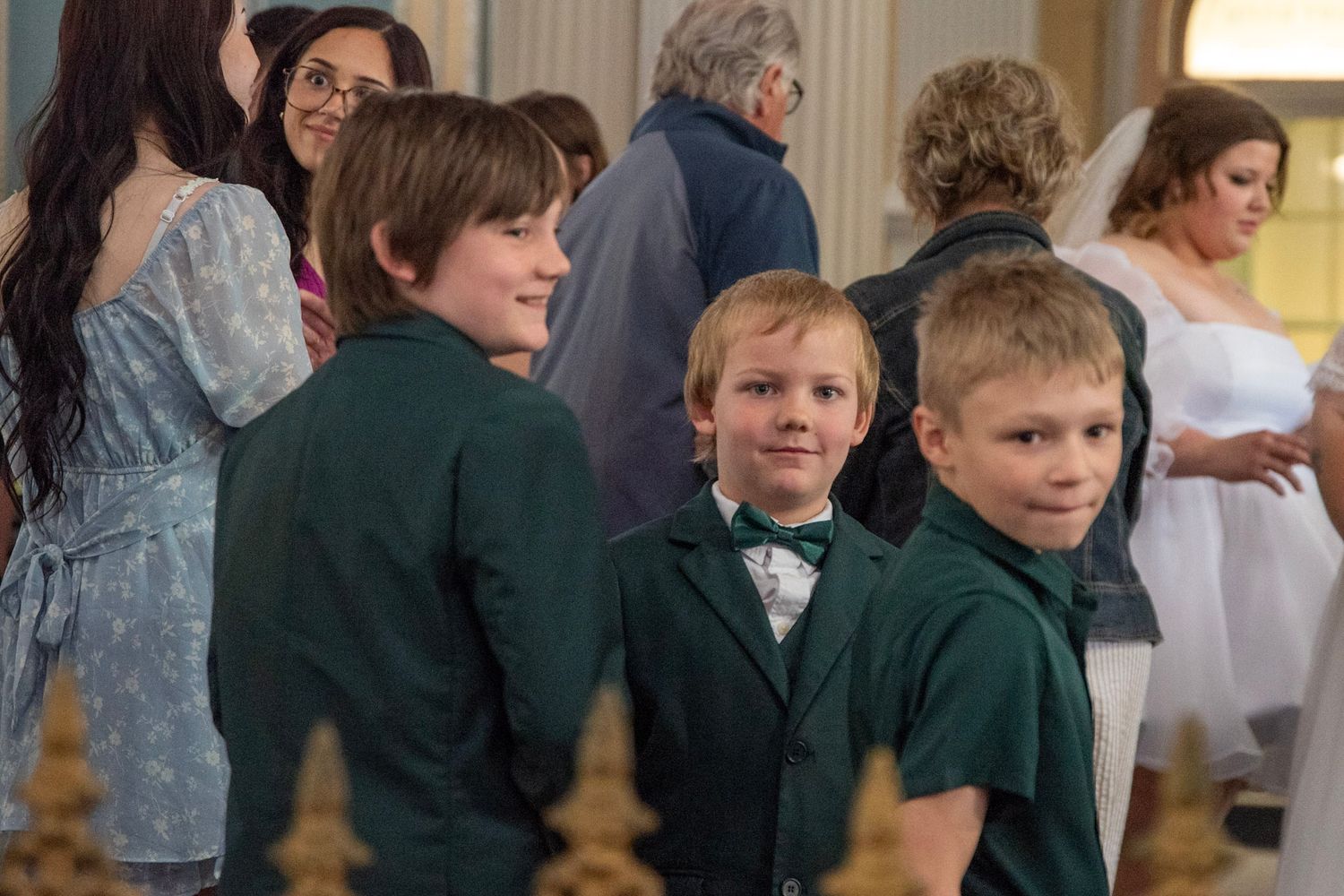 Young boys in formal attire watching a wedding ceremony in a church.