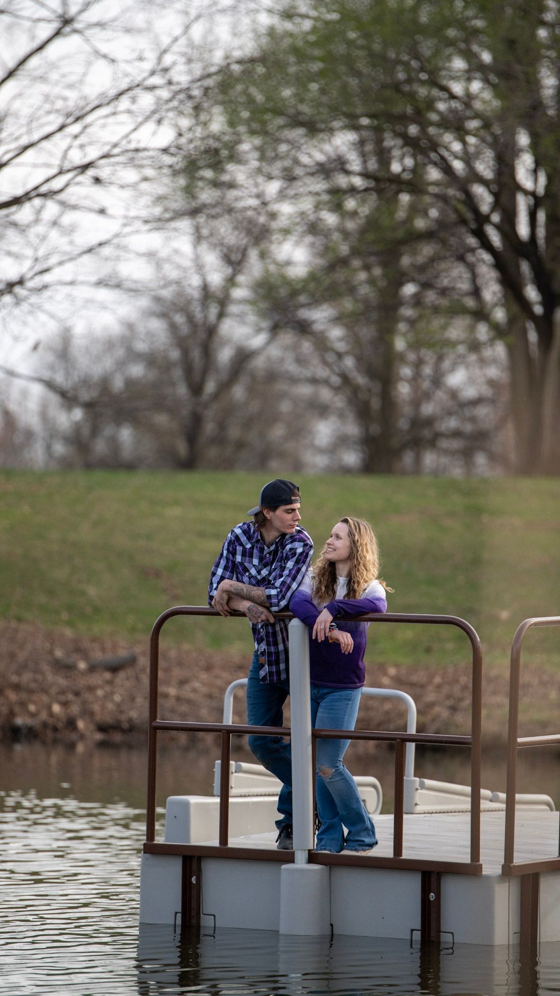 Couple sharing romantic moments on a wooden dock by the water.