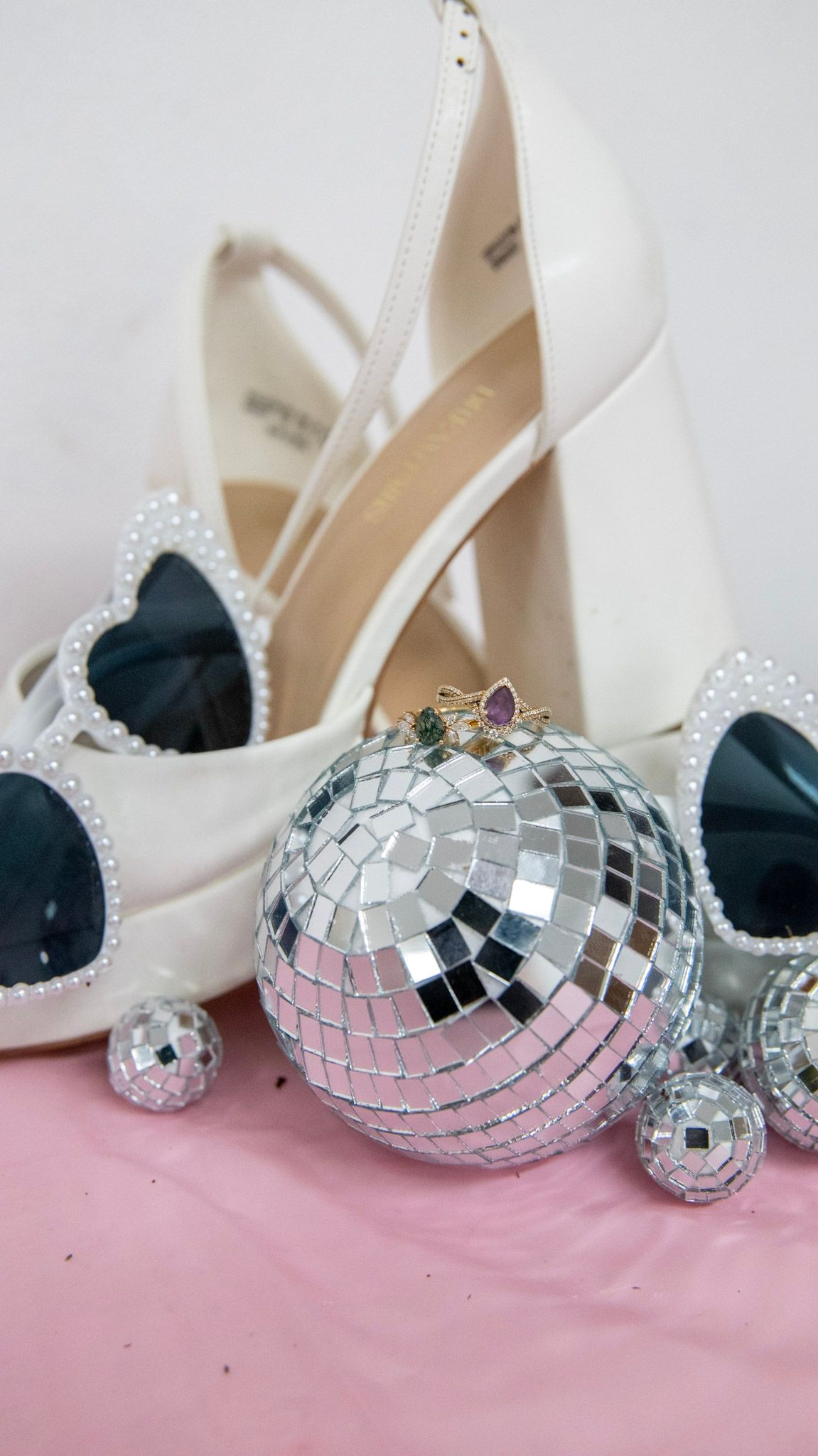 White wedding shoes displayed with decorative silver disco ball ornaments.